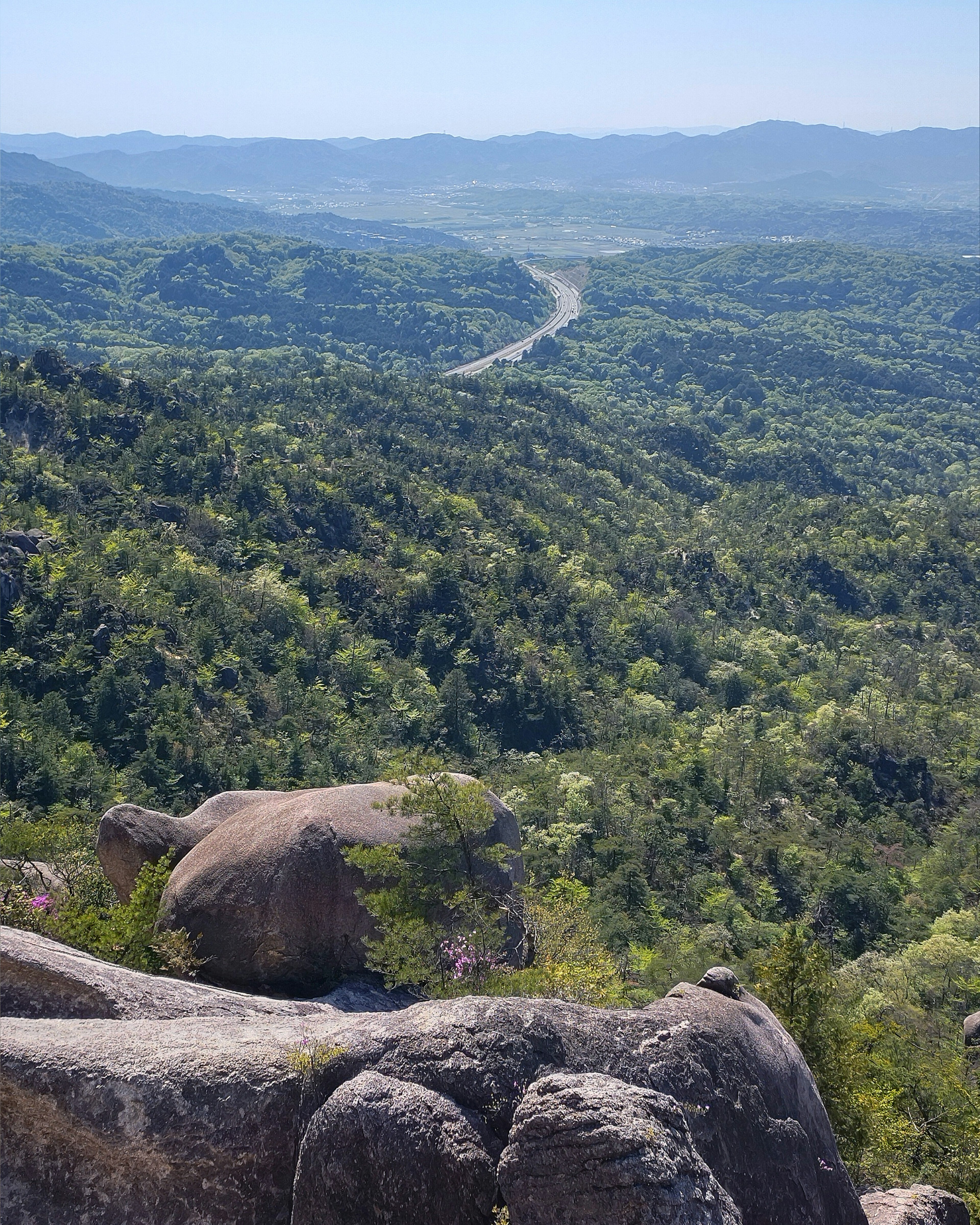 Vista escénica de montañas verdes y carretera distante desde un mirador rocoso