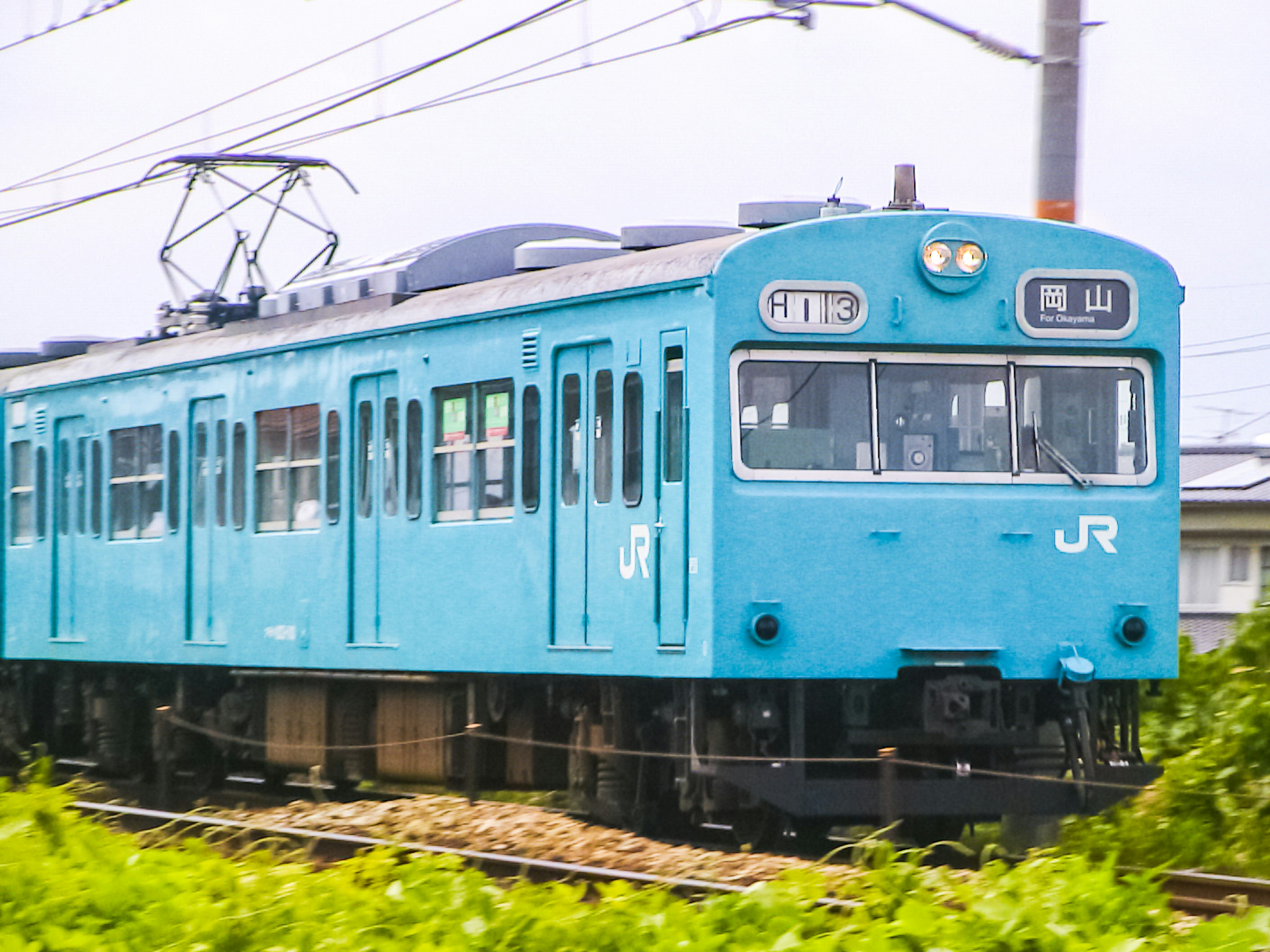 青いJR電車が線路を走る風景