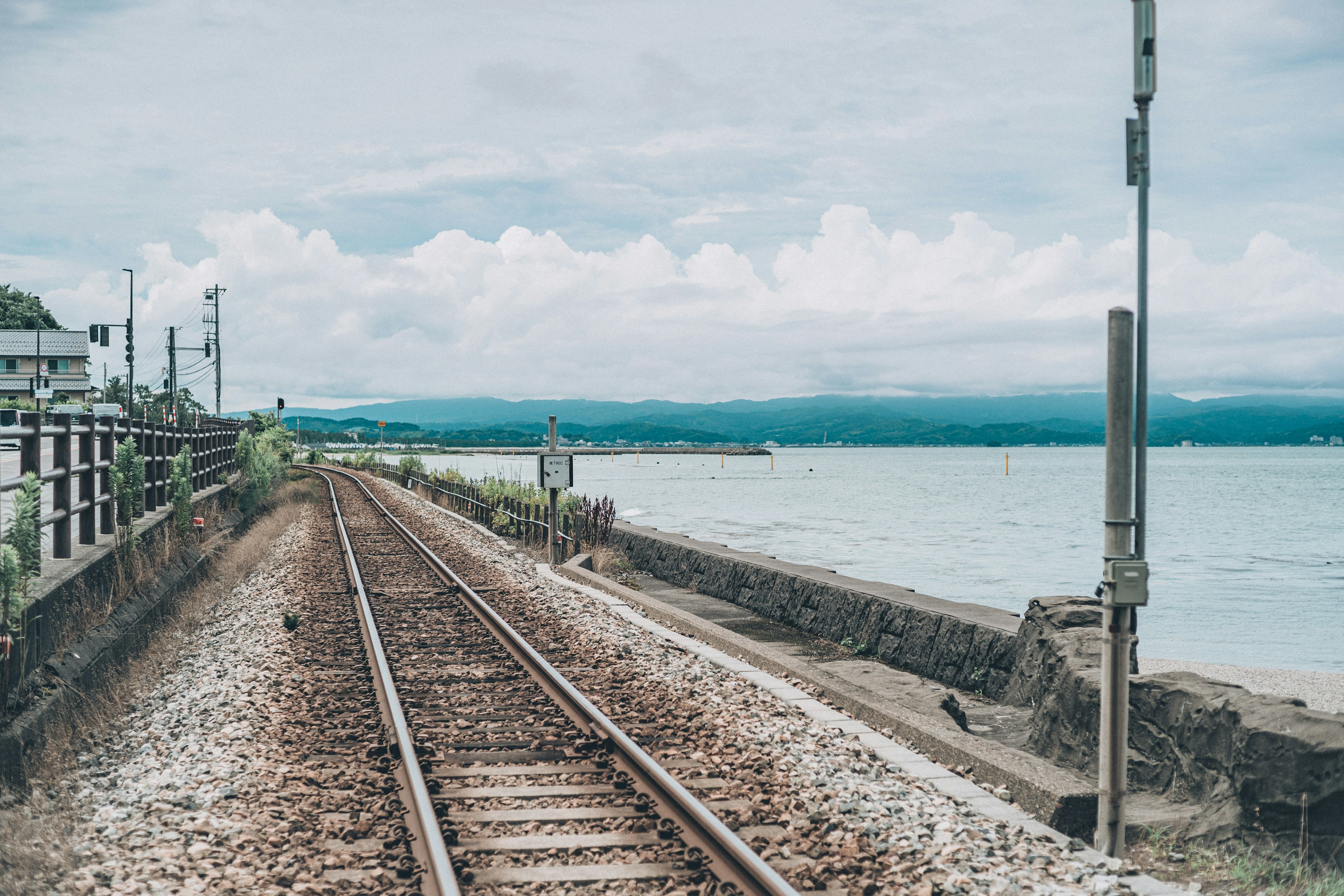 Pemandangan jalur kereta api di tepi laut dengan langit berawan