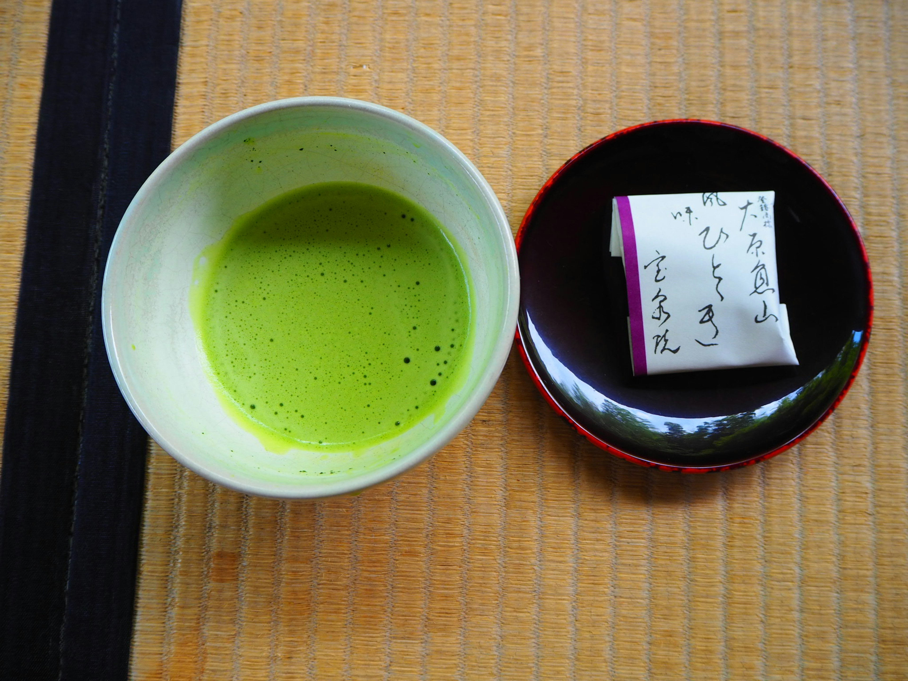 Sebuah mangkuk teh matcha dan makanan manis tradisional Jepang di atas meja