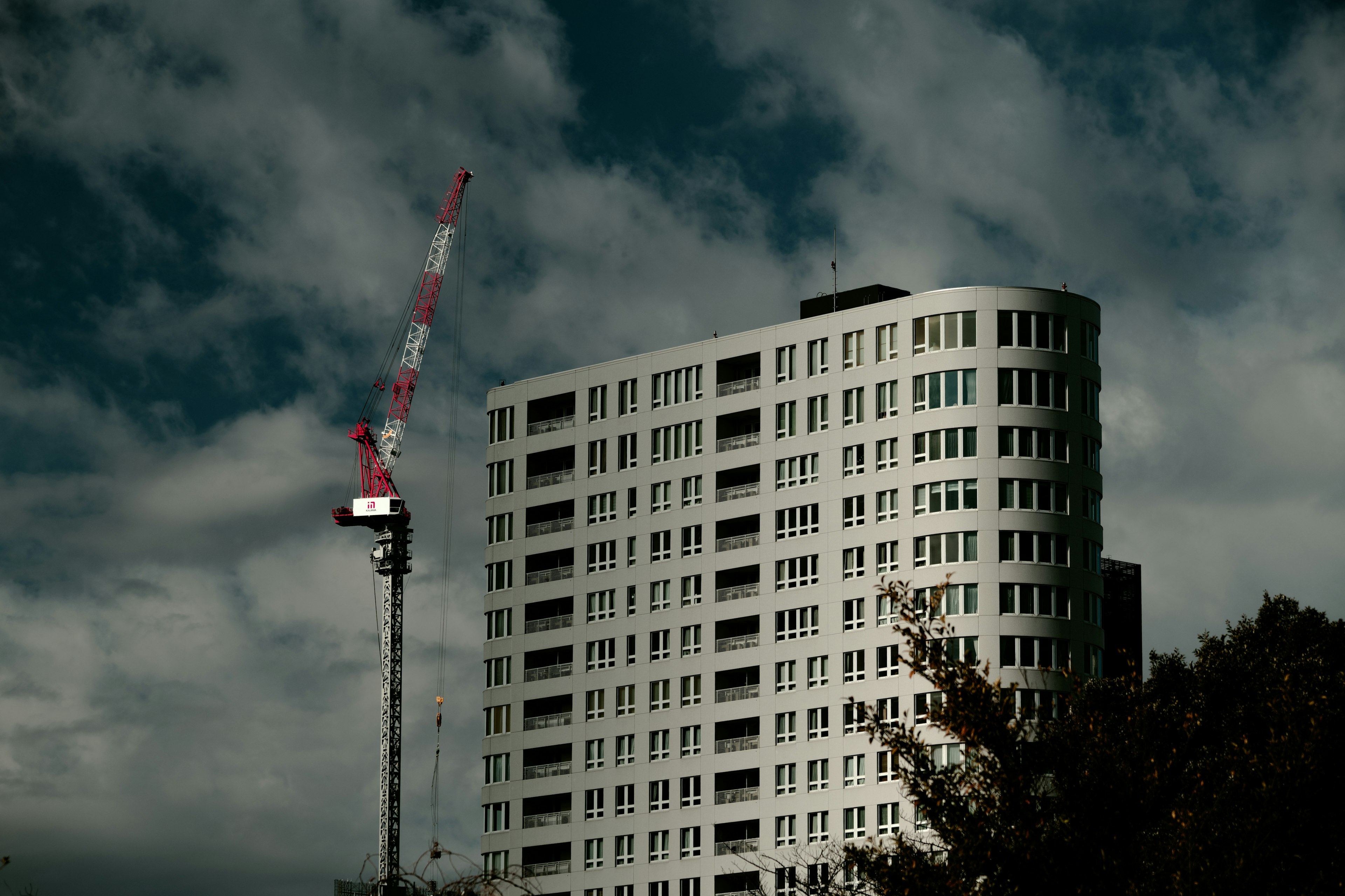 Gedung tinggi dengan crane di bawah langit gelap