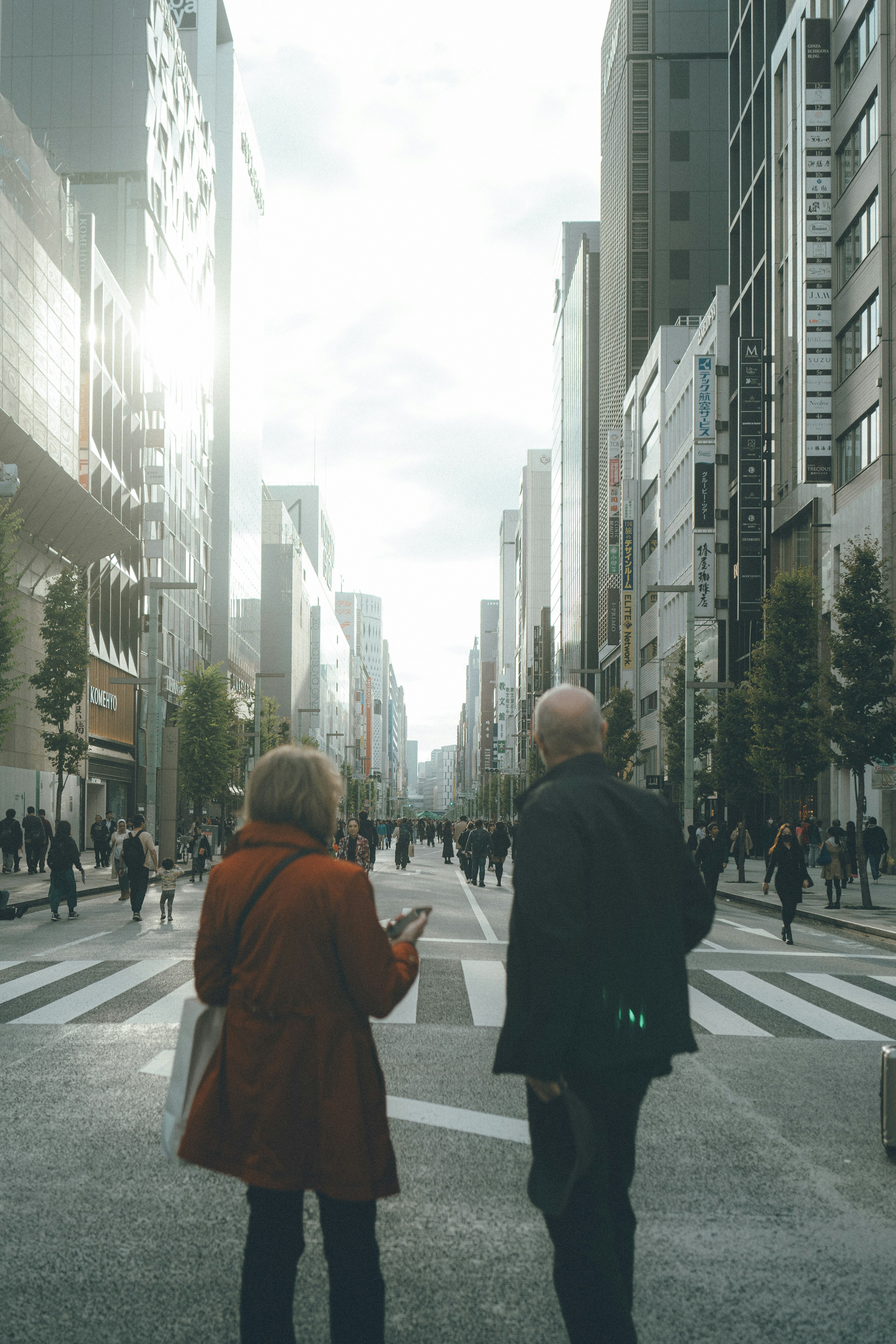 Two people walking at a city intersection with skyscrapers