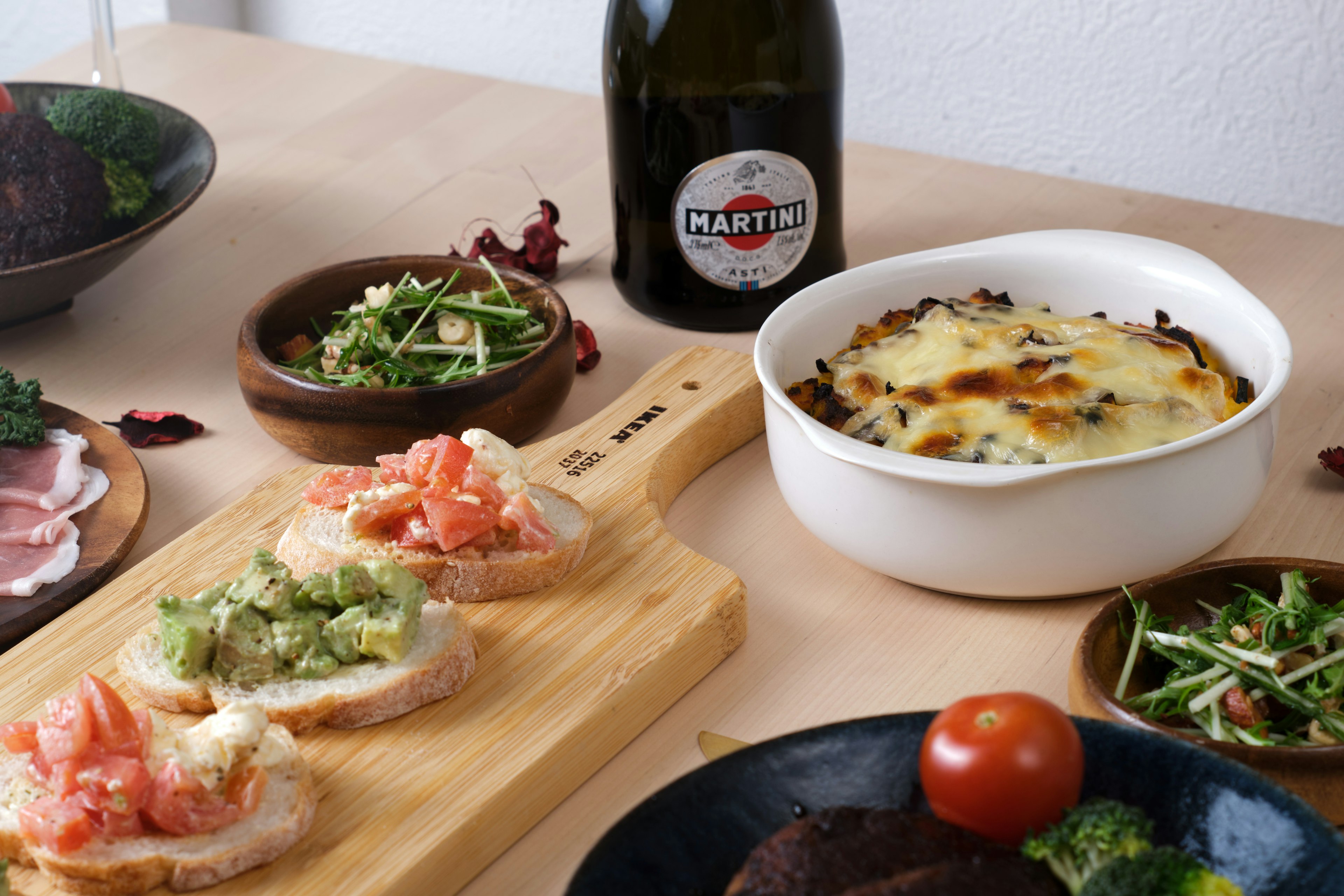 Tischdekoration mit geröstetem Brot, belegt mit Tomaten und Guacamole, neben einem Gratinschüssel