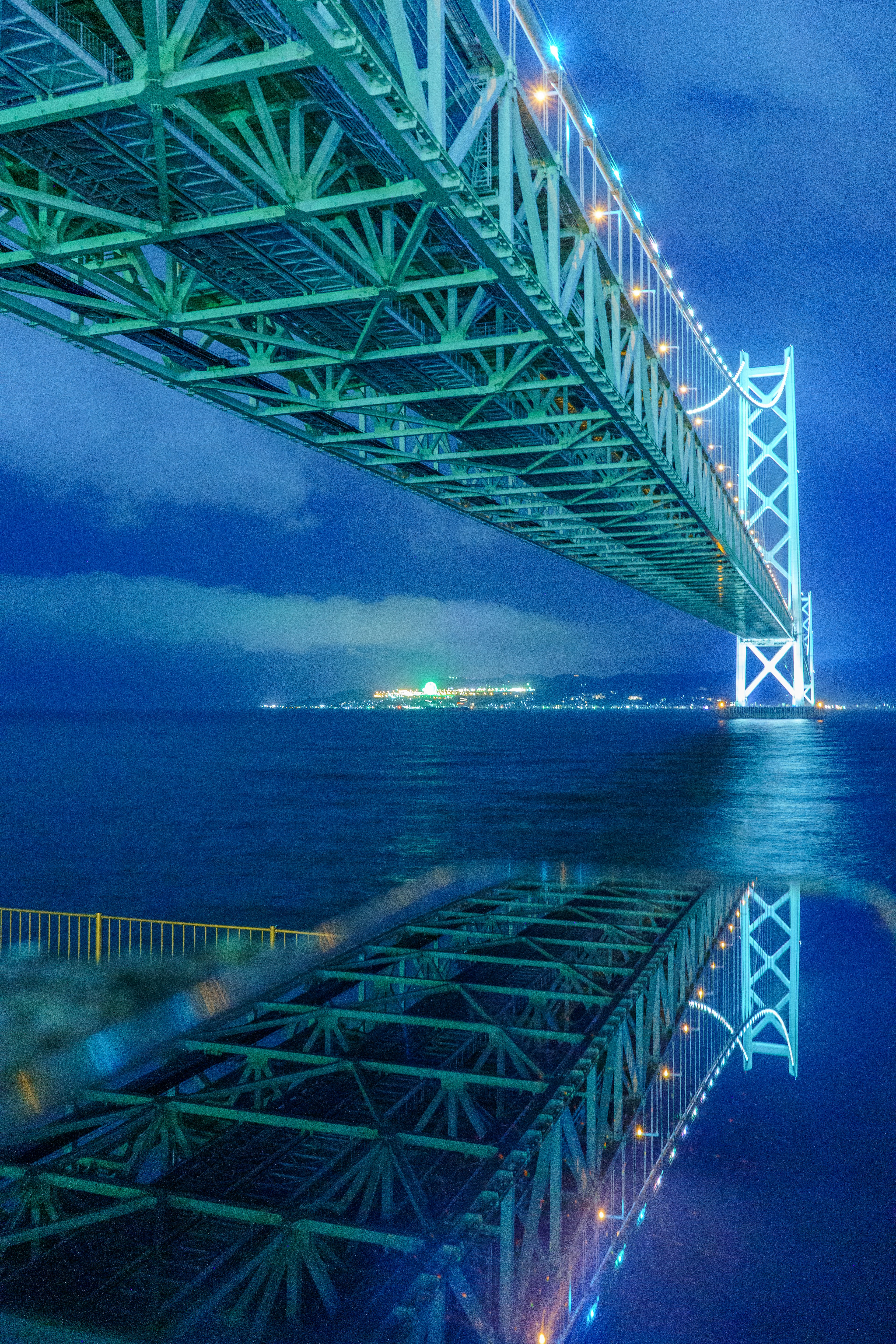 A stunning reflection of a bridge under a blue night sky on the water surface