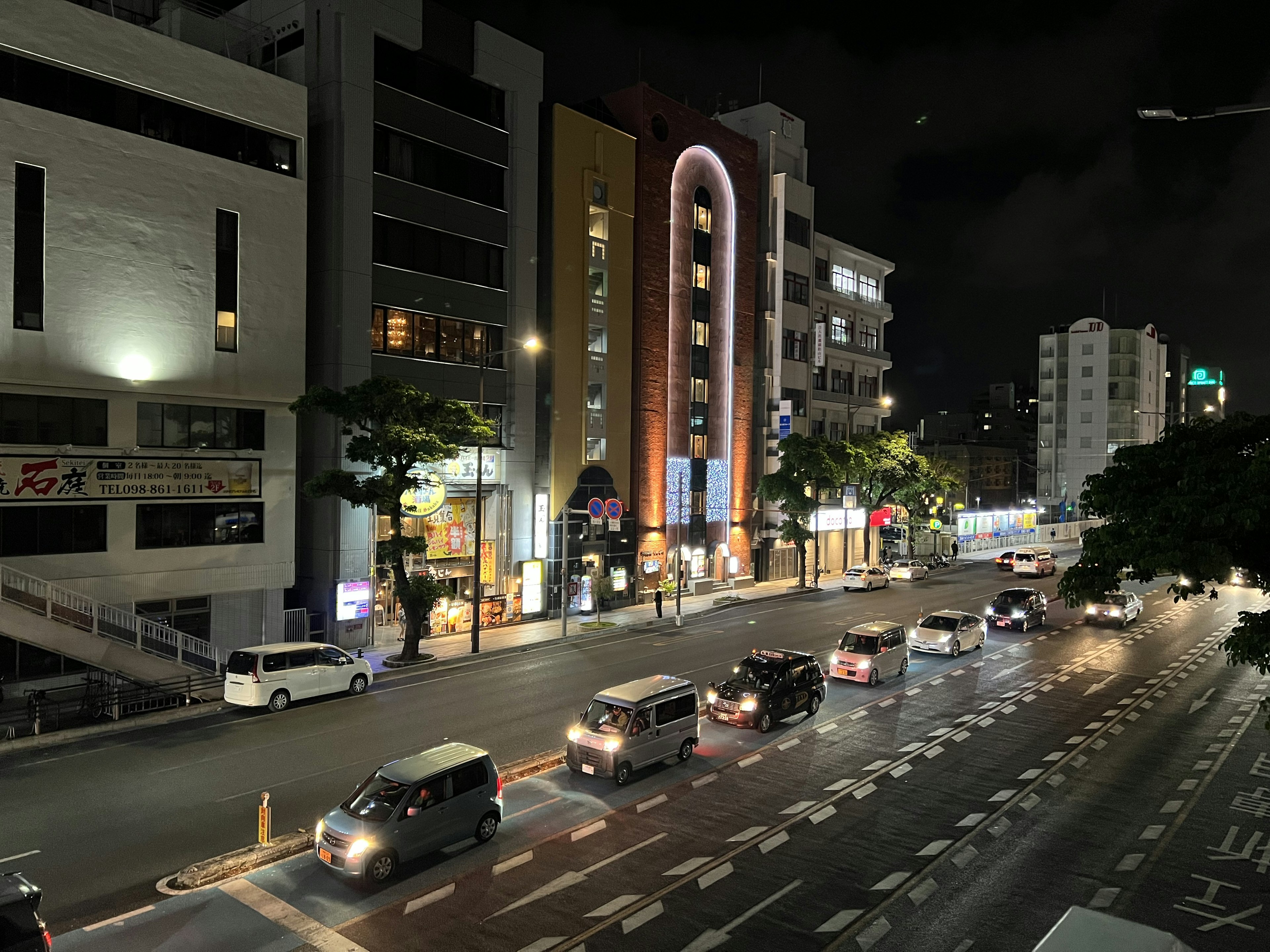 Paisaje urbano nocturno con coches alineados y edificios iluminados