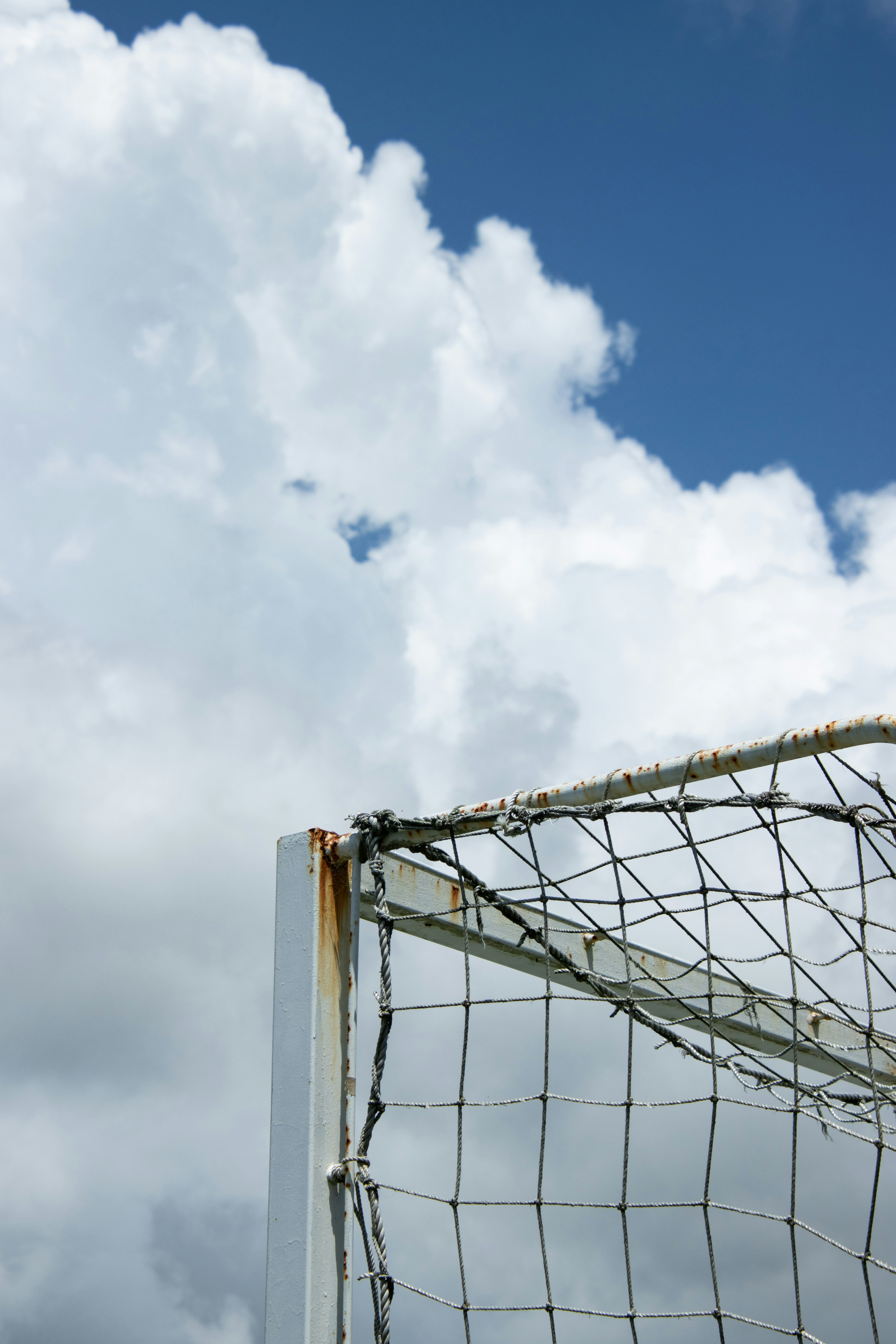 Part of a soccer goal against a blue sky with clouds