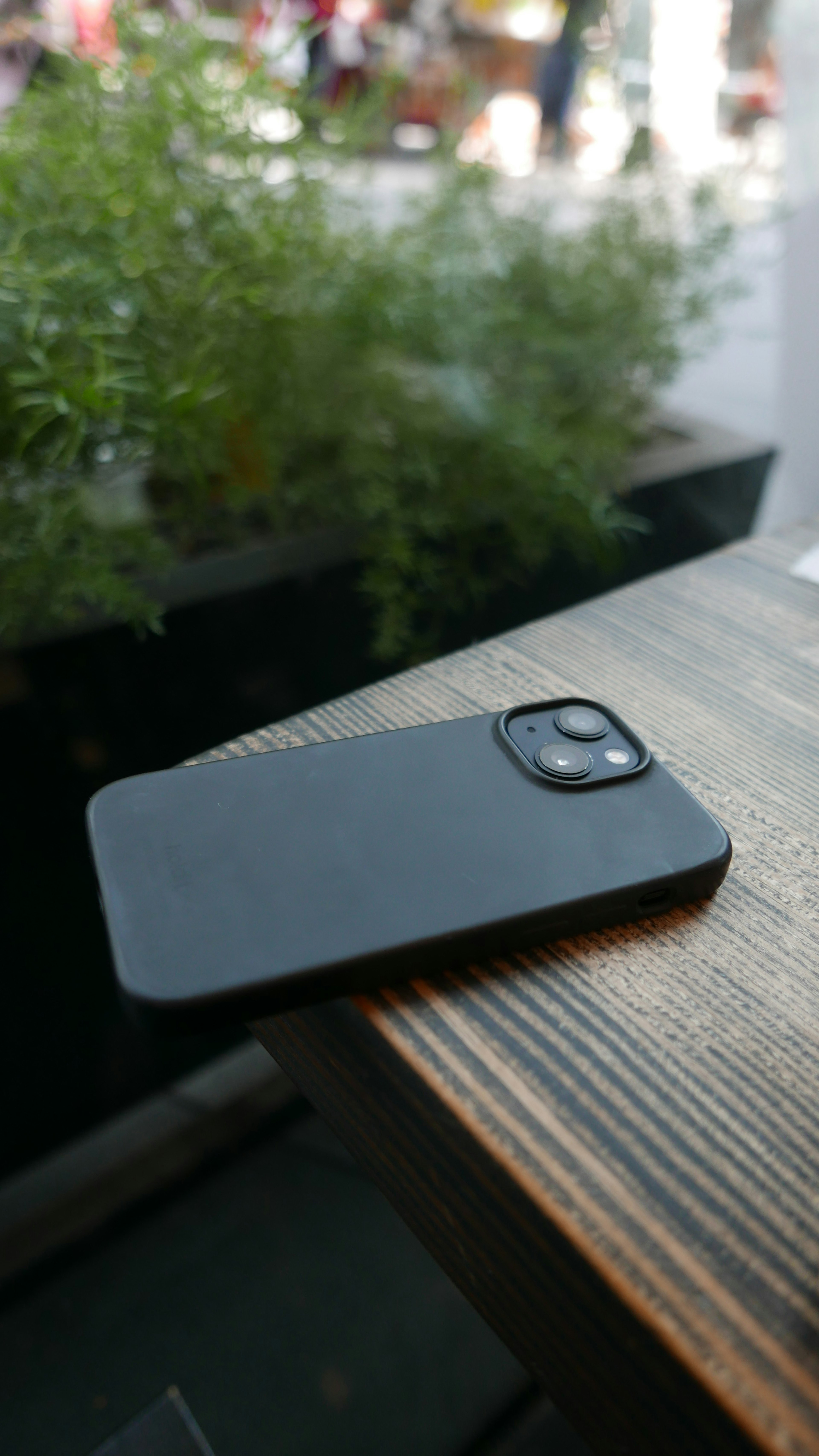 A black smartphone resting on a wooden table