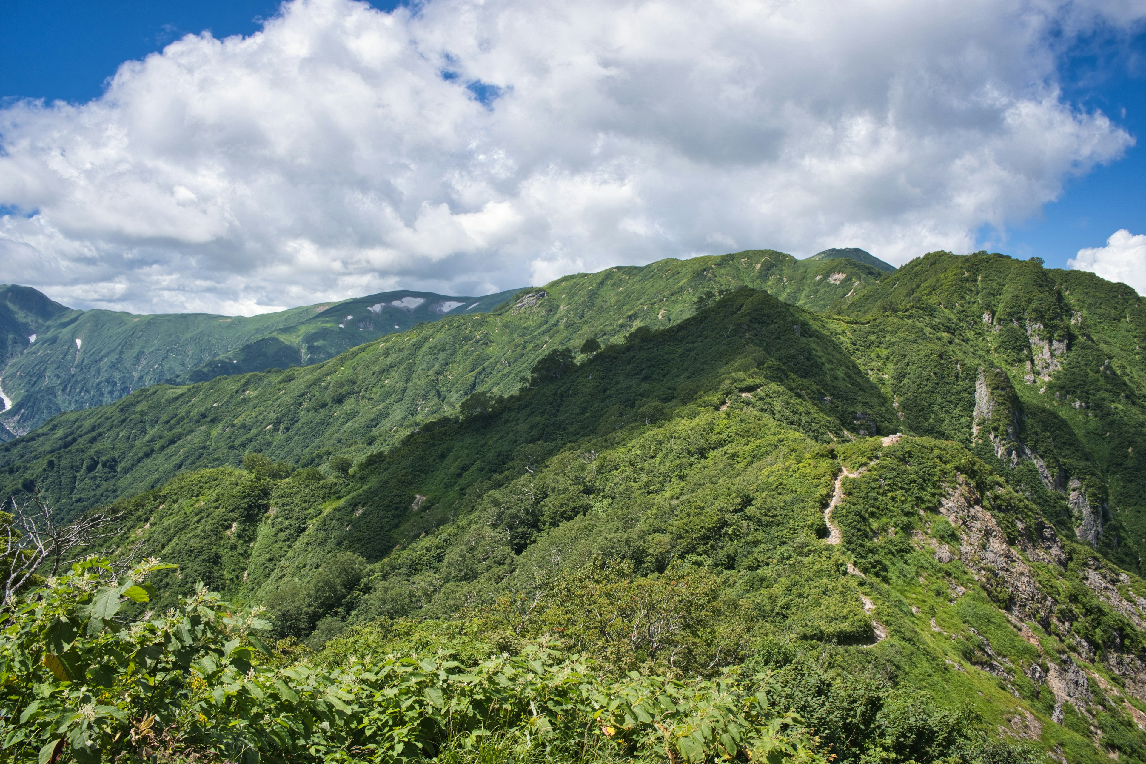 Montañas verdes bajo un cielo azul con nubes dispersas