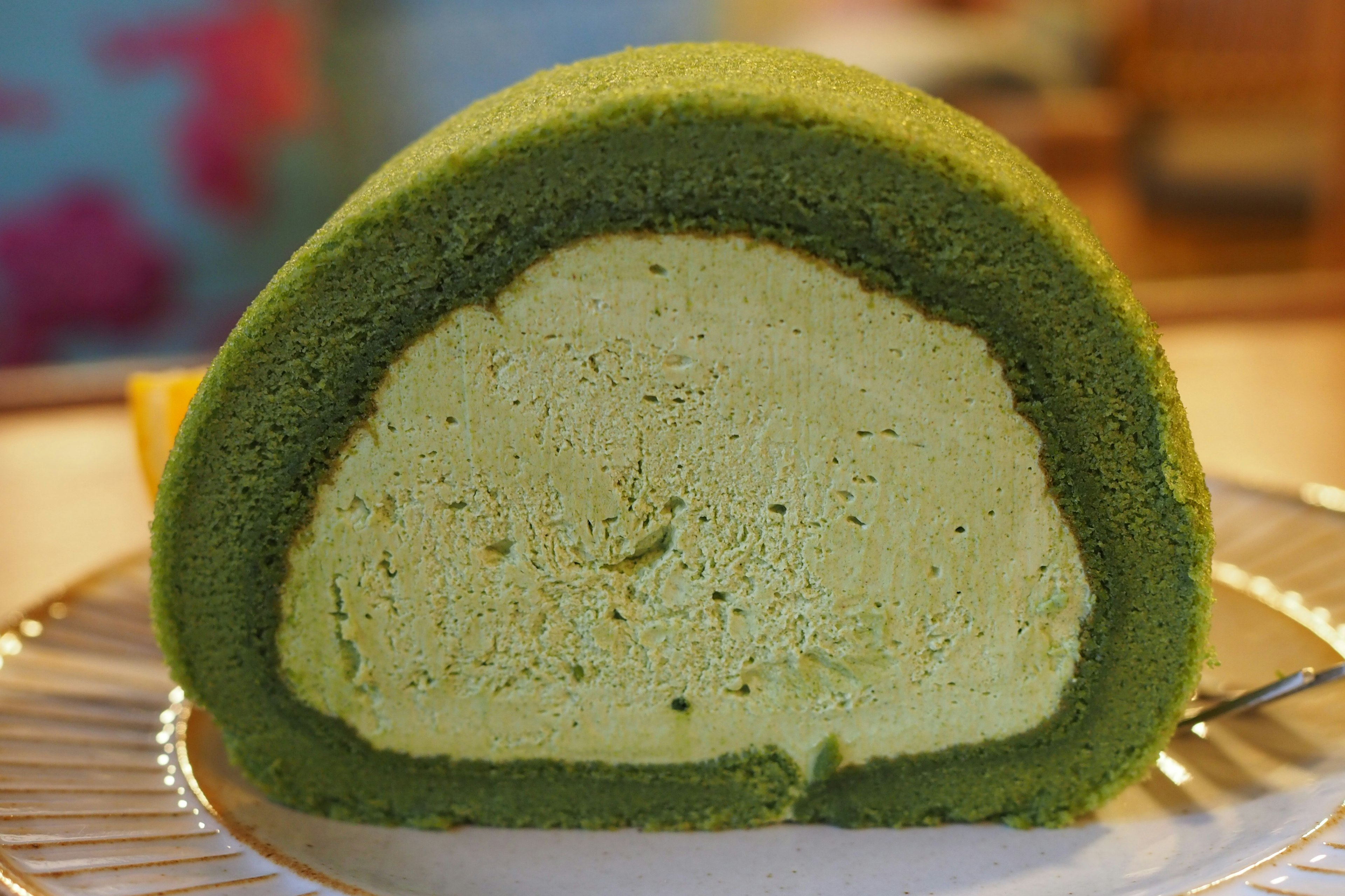 Sezione di una torta arrotolata al matcha con spugna verde e ripieno