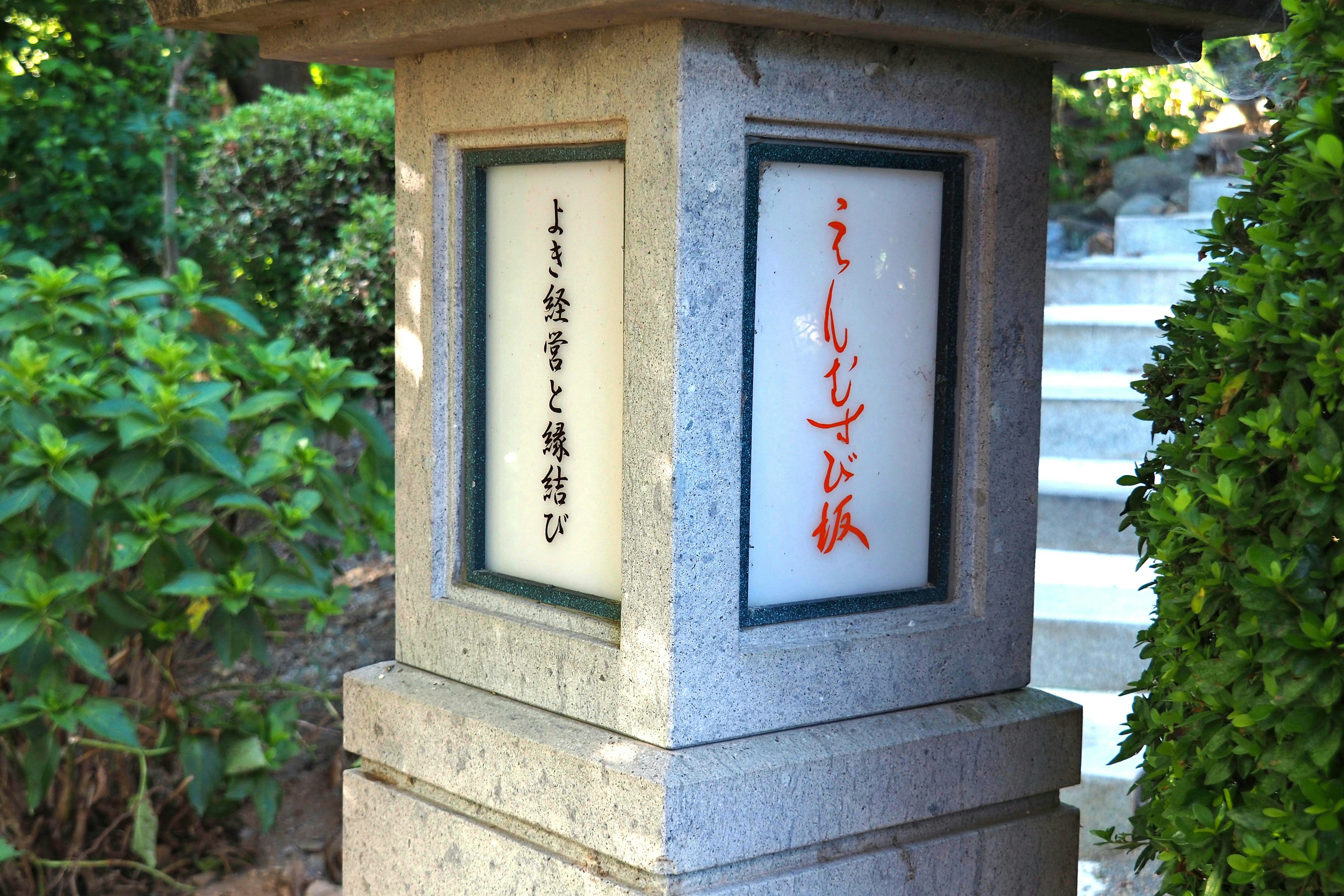 Steinlaterne mit japanischen Schriftzeichen und üppigen grünen Pflanzen