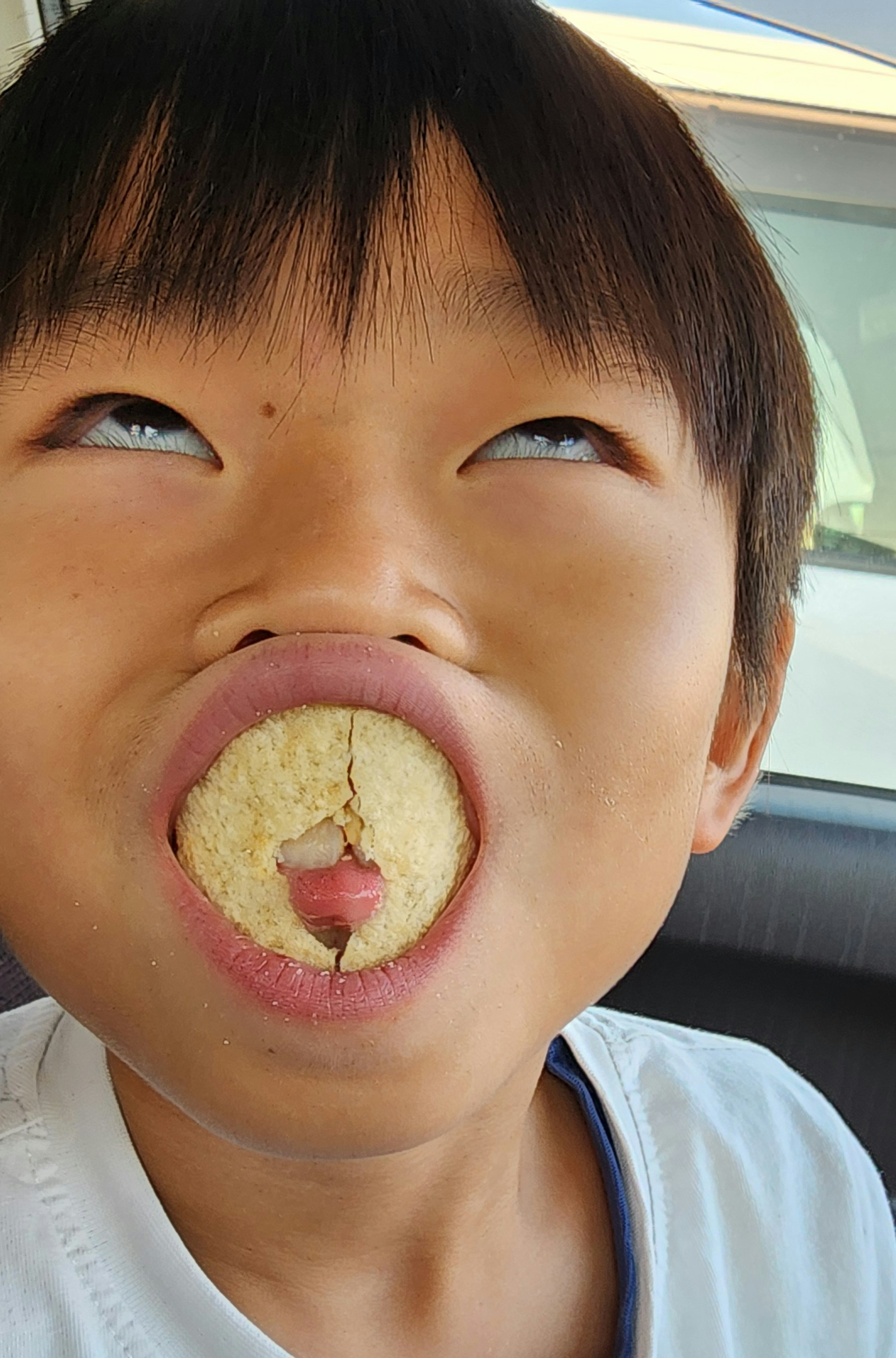 Kind macht ein lustiges Gesicht mit einem Snack im Mund