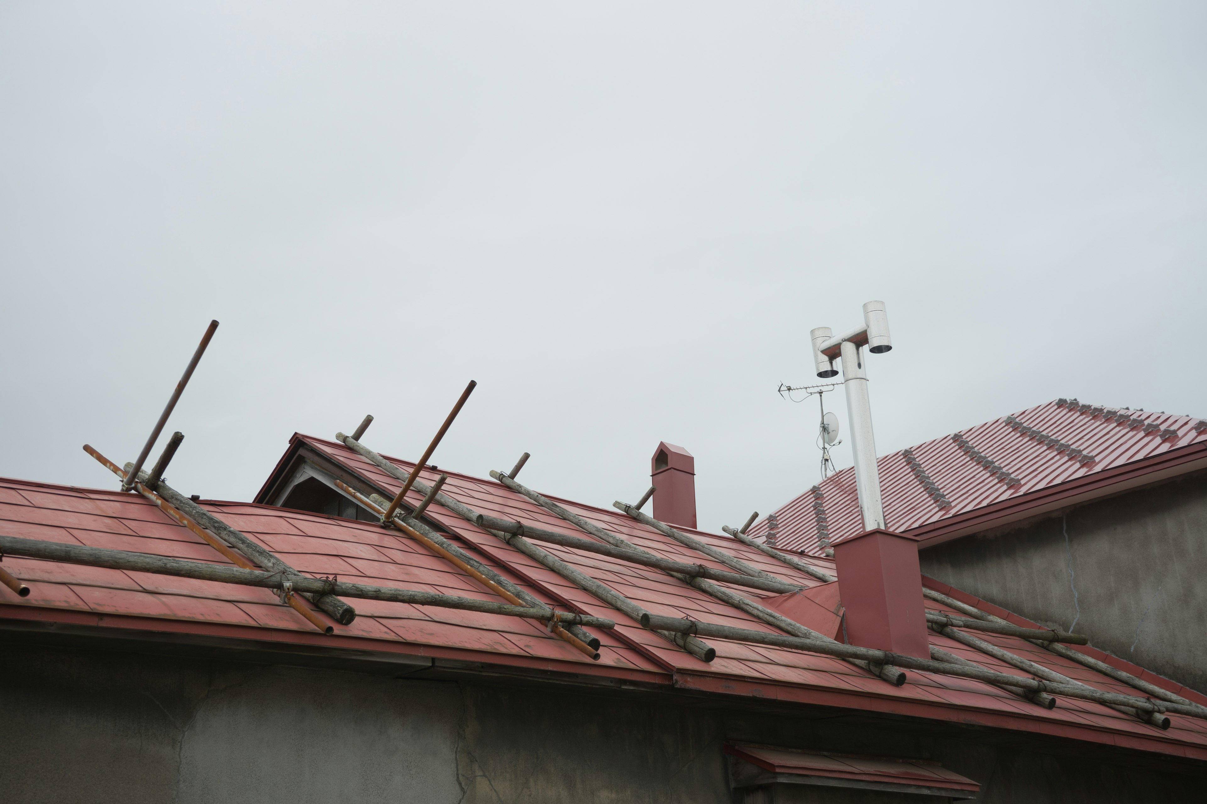 Vista de un edificio con techo rojo y soportes metálicos bajo un cielo nublado