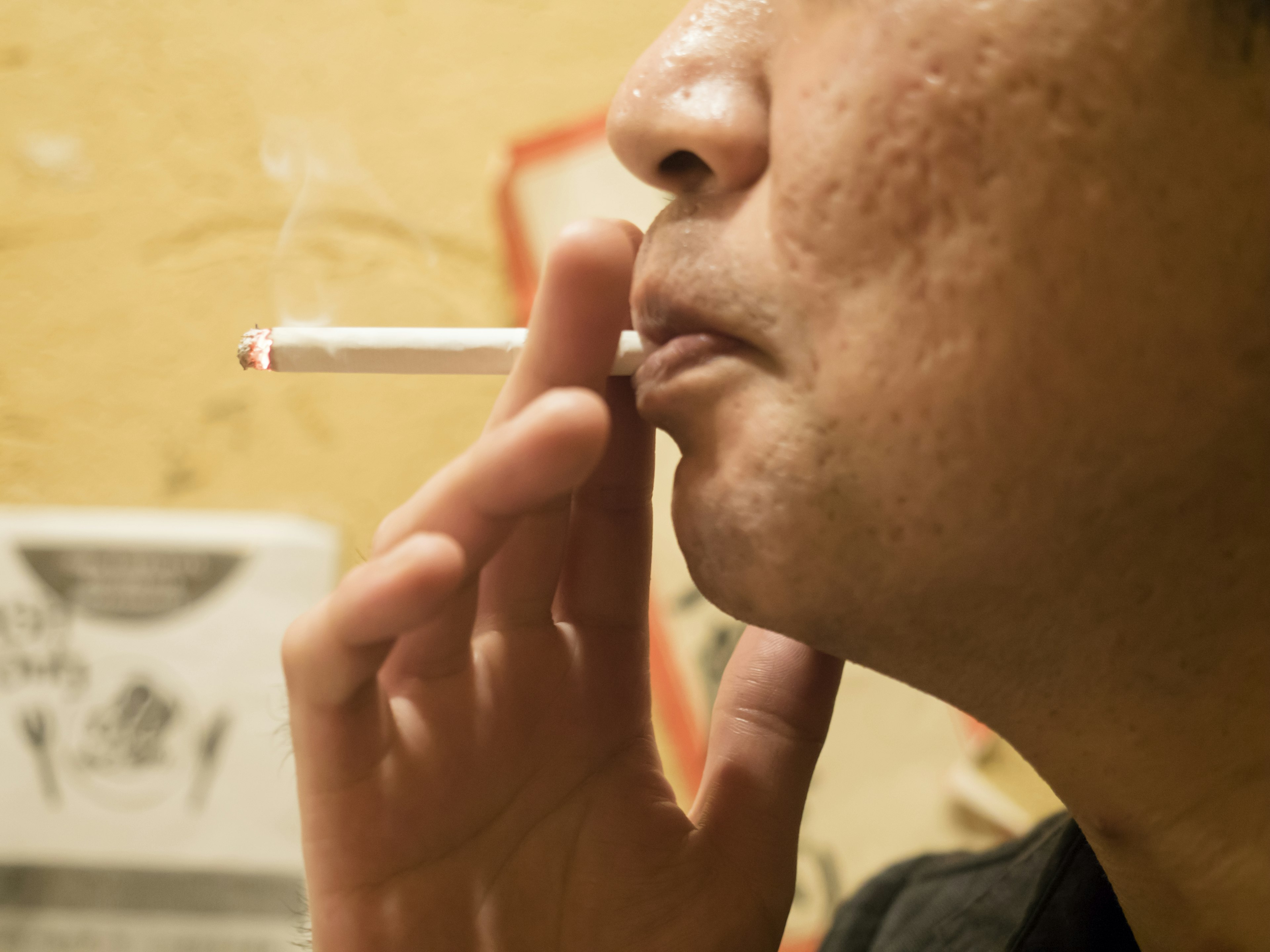 Side profile of a man smoking a cigarette with smoke