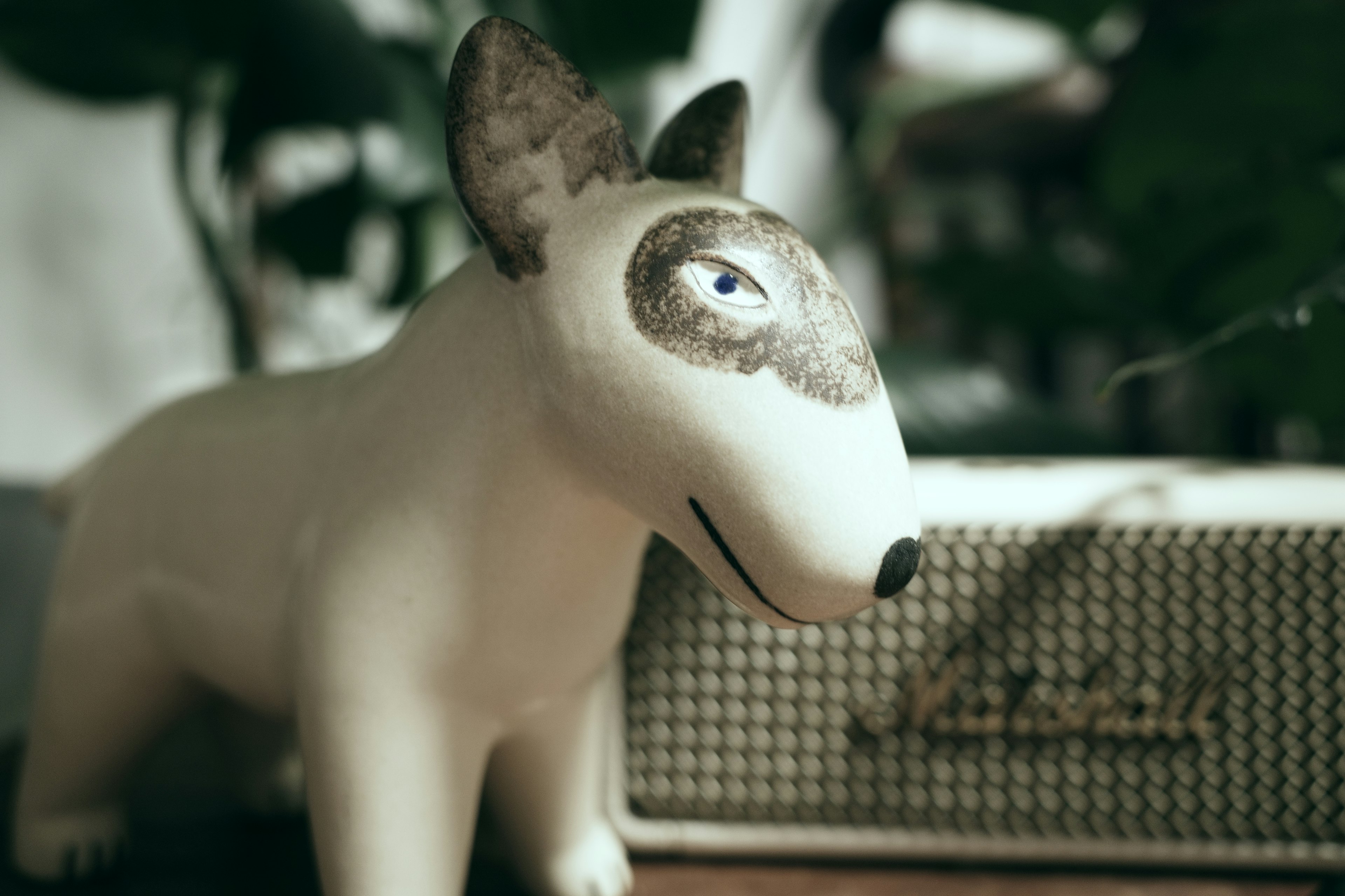 Une figurine de chien blanc à côté de plantes vertes