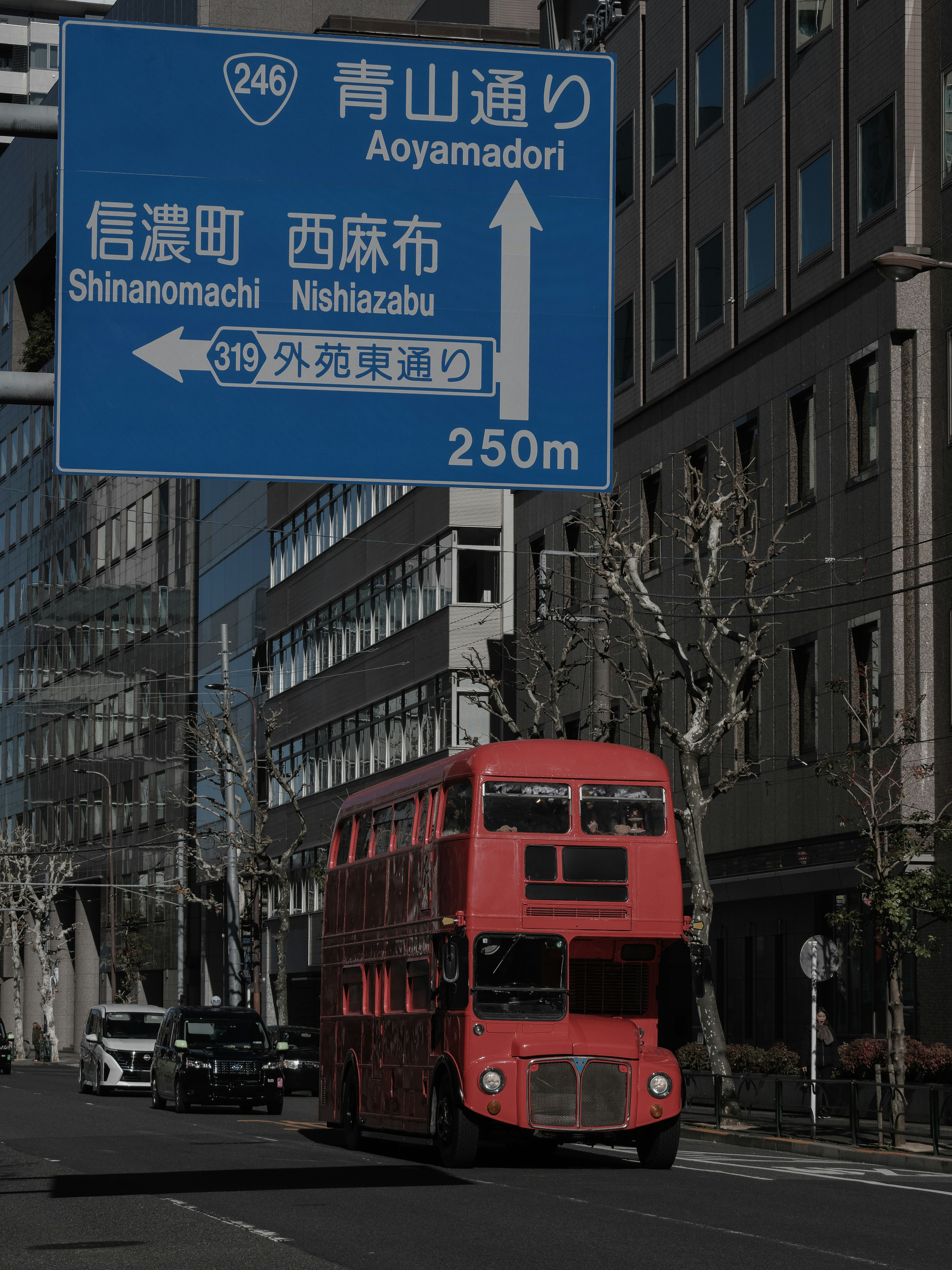 Autobus à impériale rouge avec un panneau routier bleu dans un cadre urbain