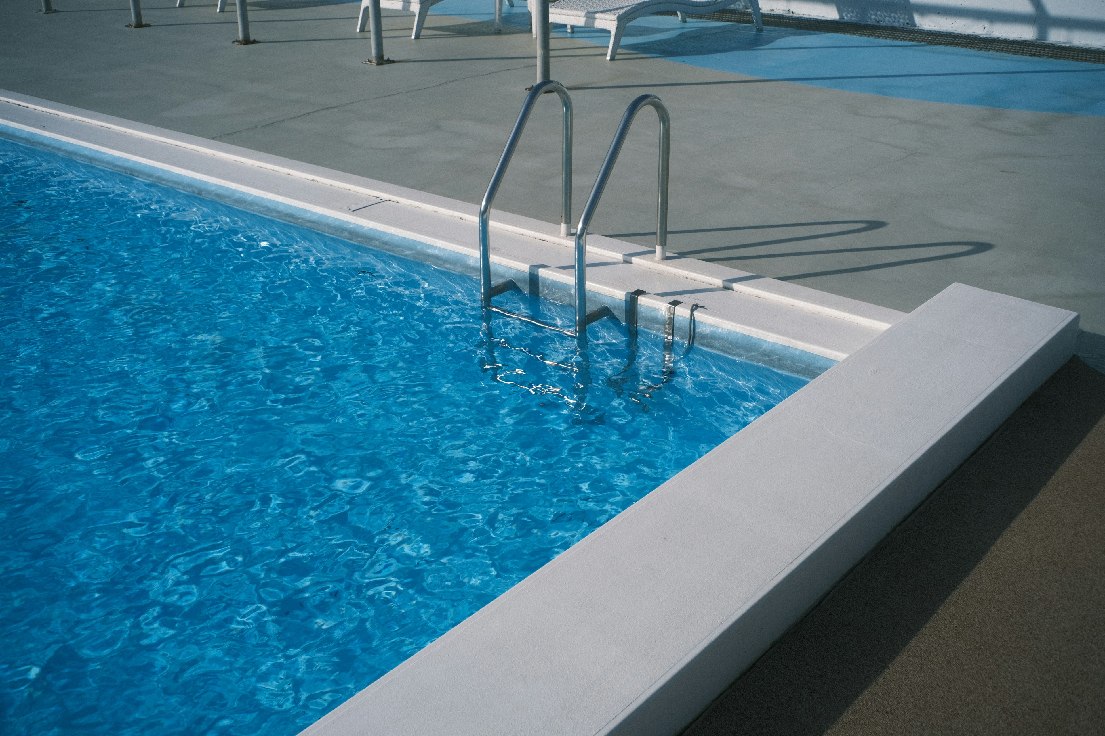 Vue d'une piscine bleue avec des marches en métal sur le côté