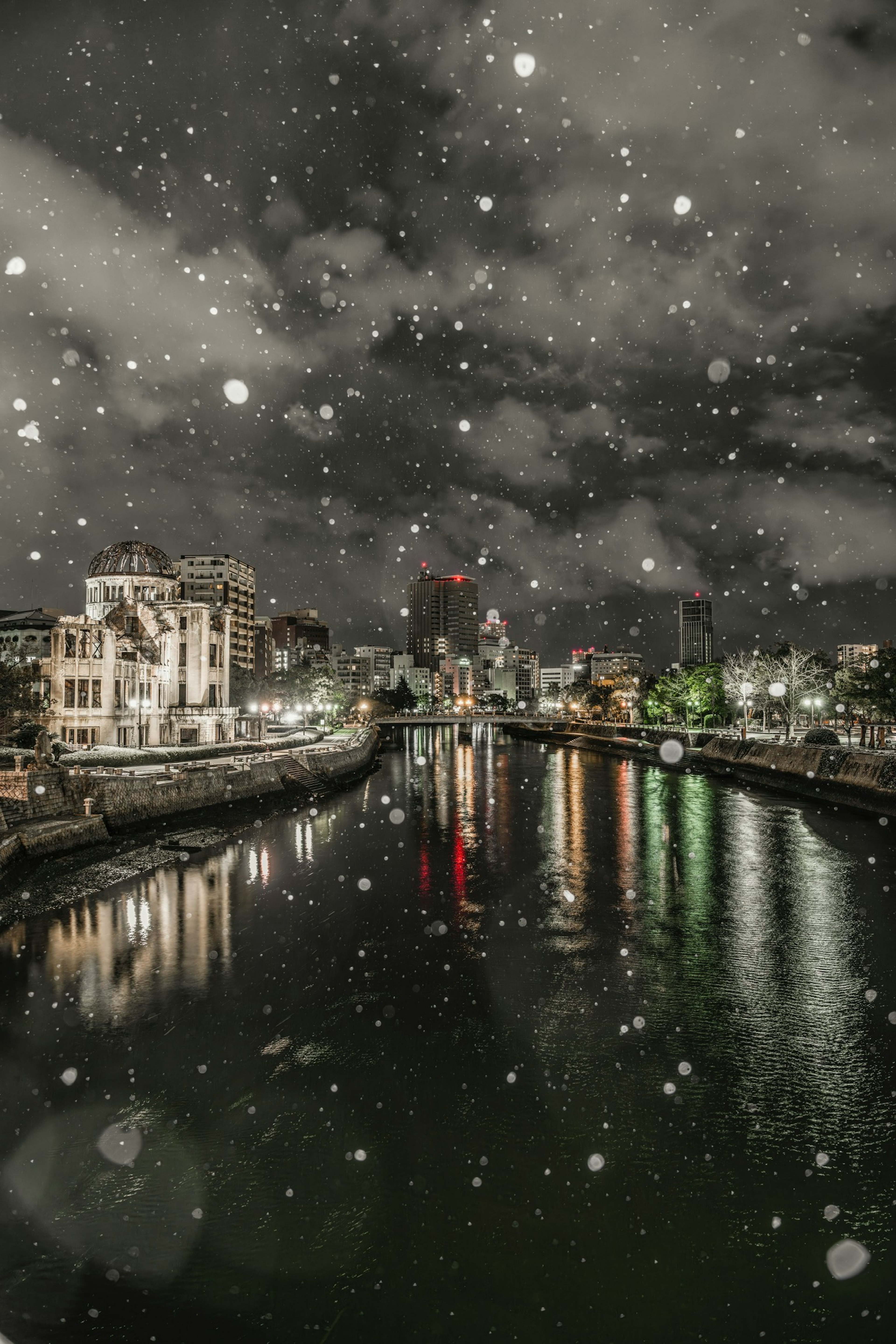 Paesaggio urbano notturno con neve che cade sul fiume e edifici illuminati