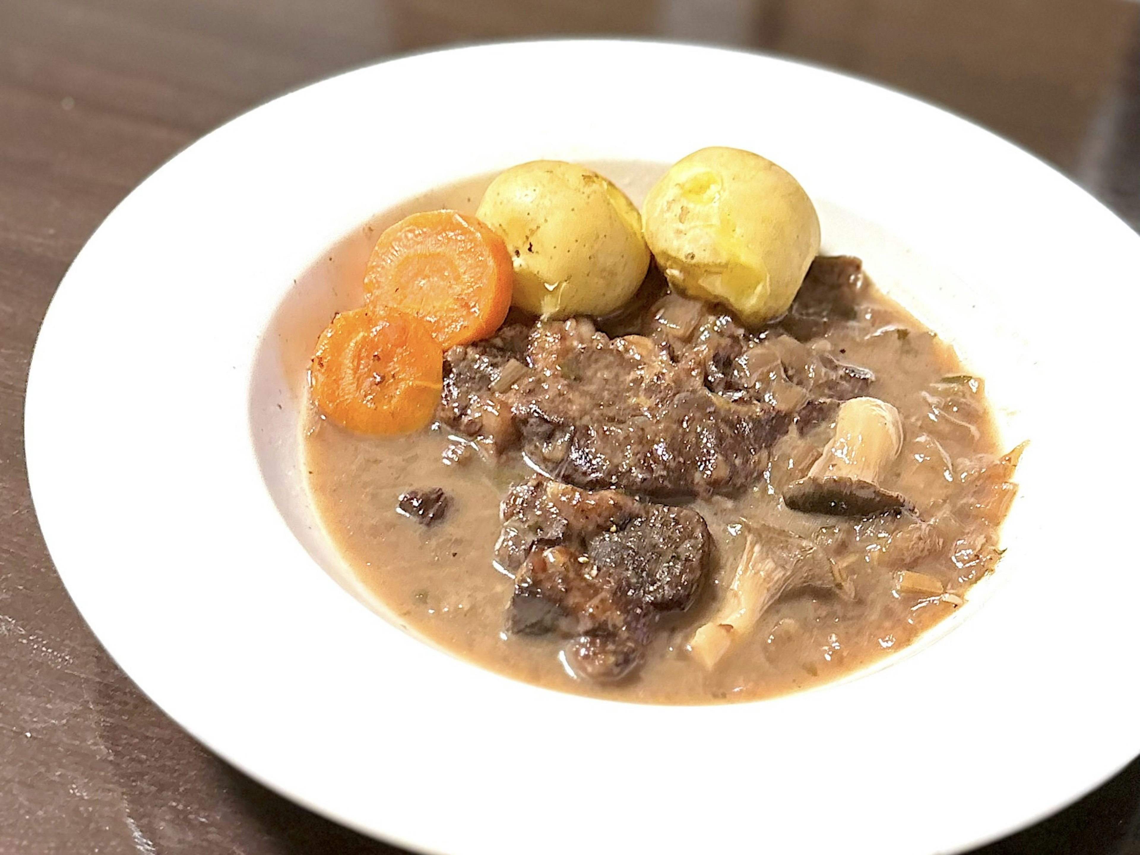 Ein Teller Rindfleisch-Eintopf, serviert mit Karotten und Kartoffeln