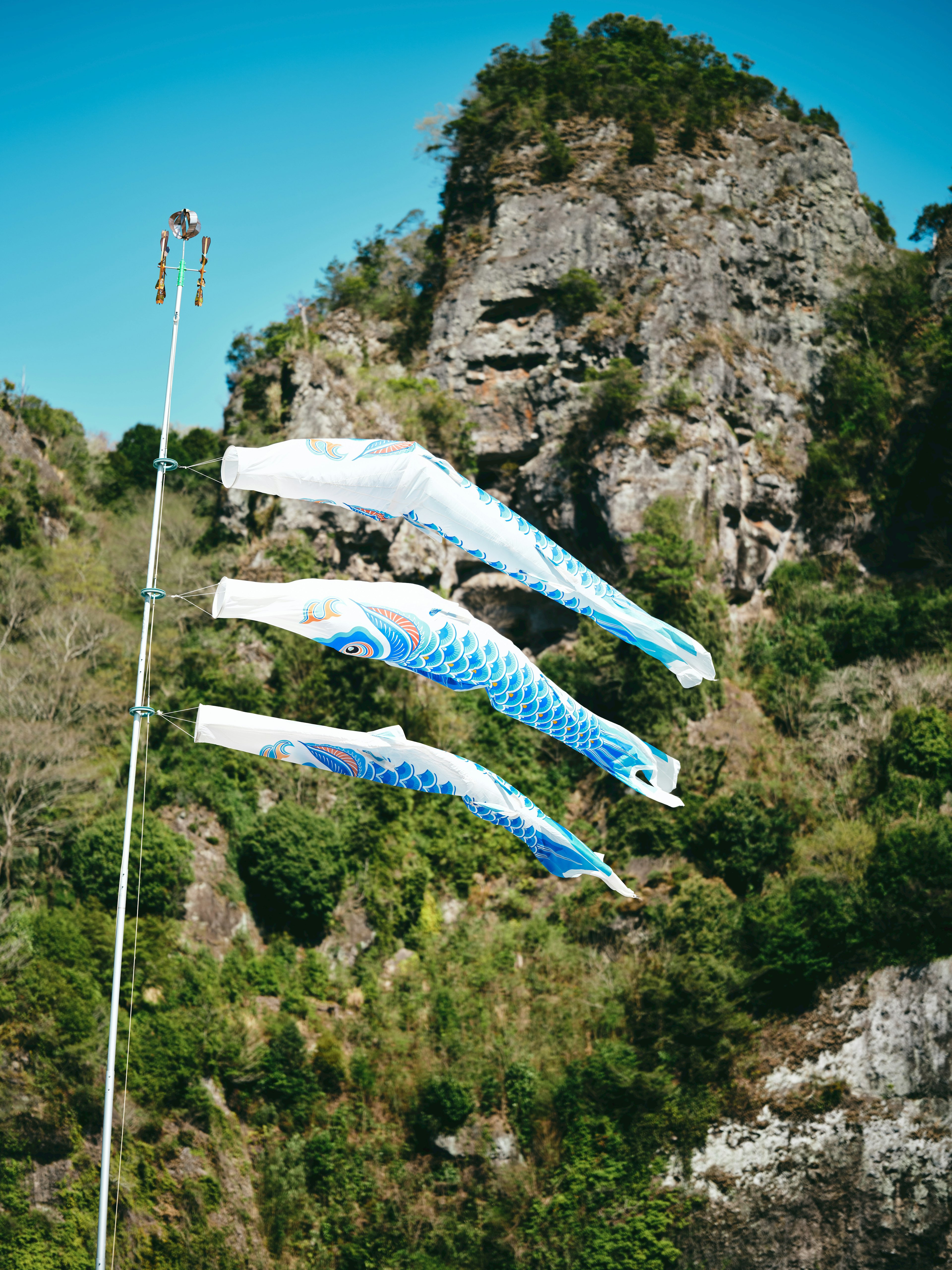 Koinobori, die vor einer bergigen Kulisse fliegen