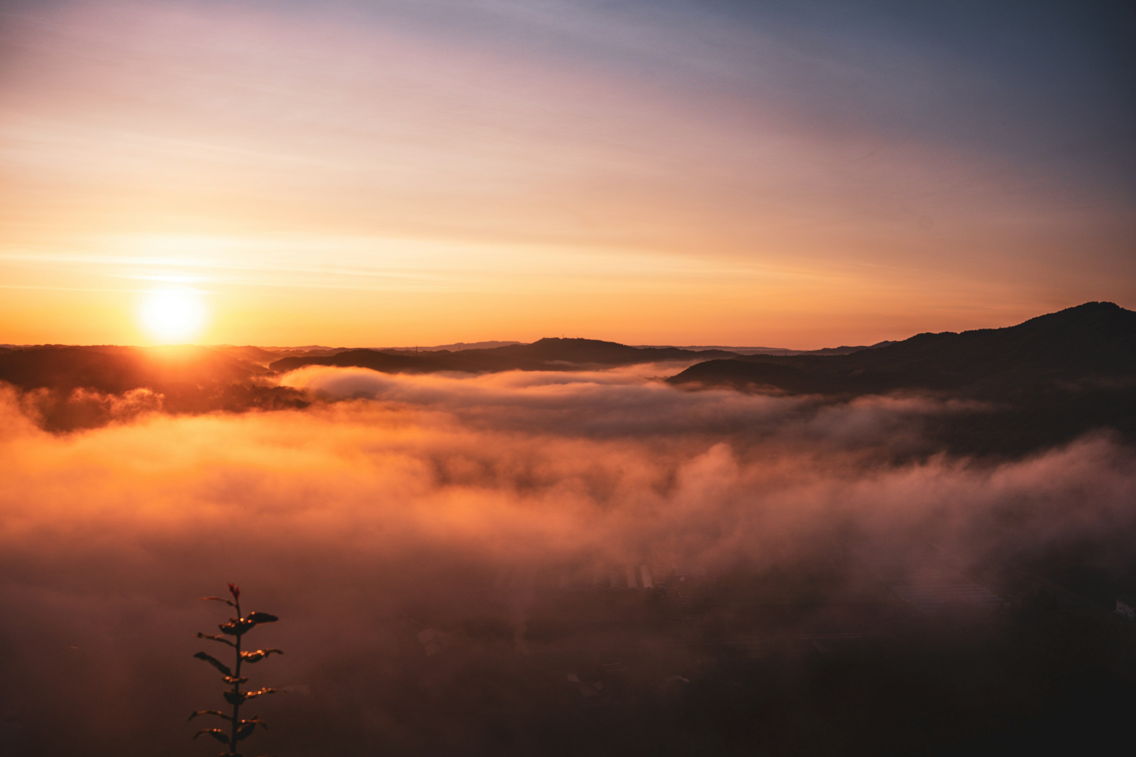 Lever de soleil sur une mer de nuages avec des montagnes au loin