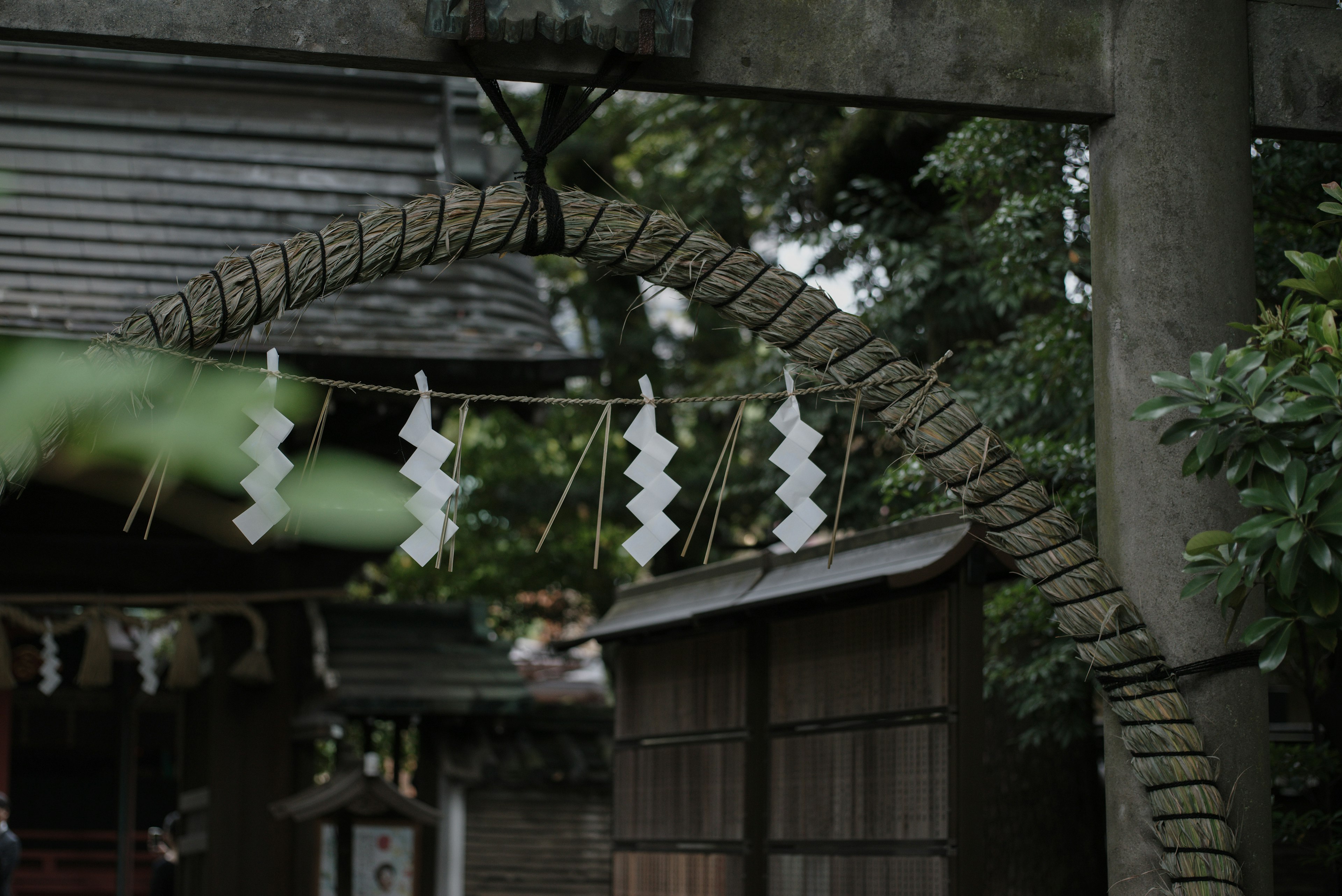 神社の鳥居に掛けられた白いしめ縄と飾りが見える