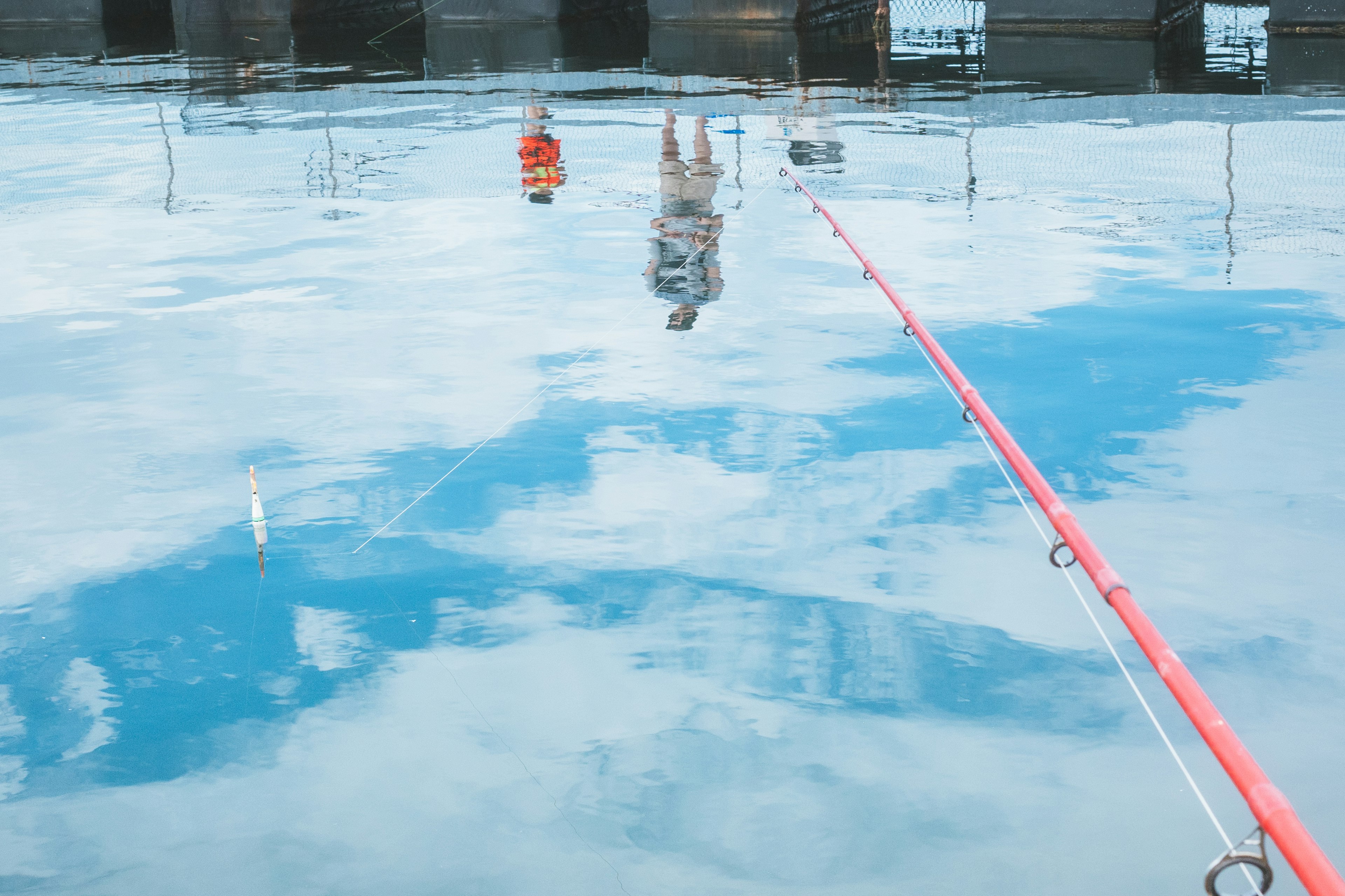 Reflejo del cielo y figura en la superficie del agua con caña de pescar