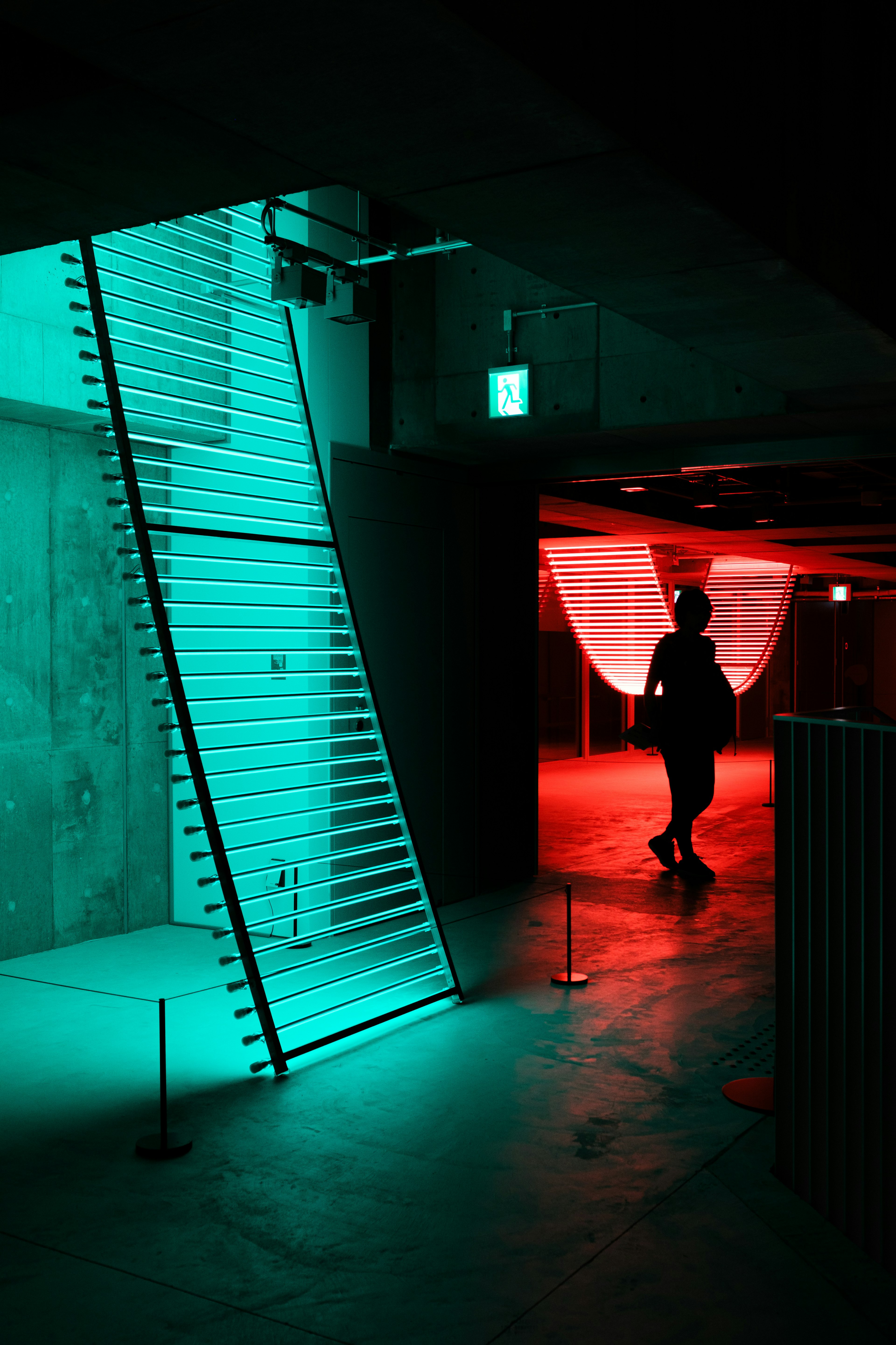 A silhouette walks through a modern space illuminated by blue and red lights