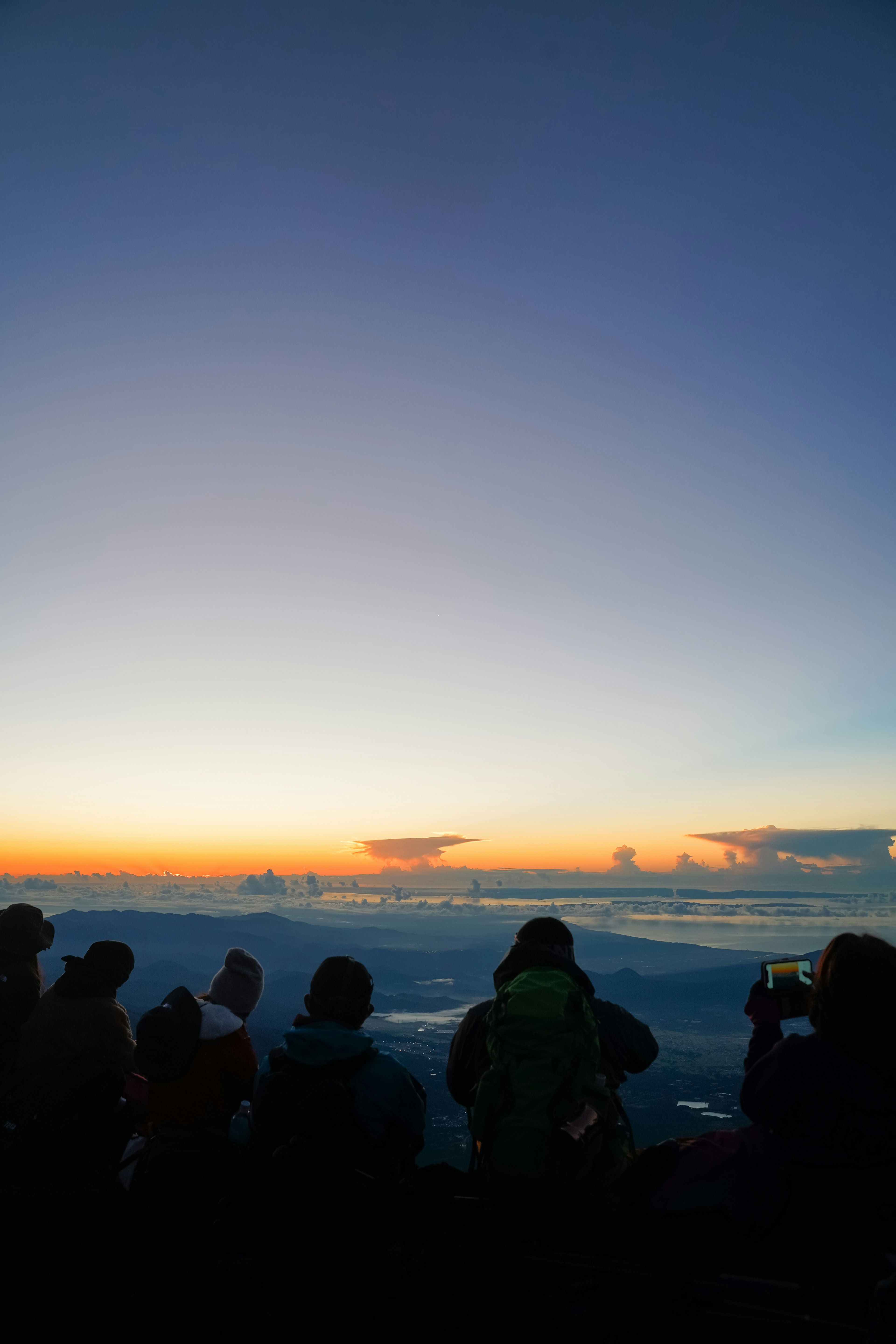 Siluet orang-orang yang melihat matahari terbit yang indah dari puncak gunung