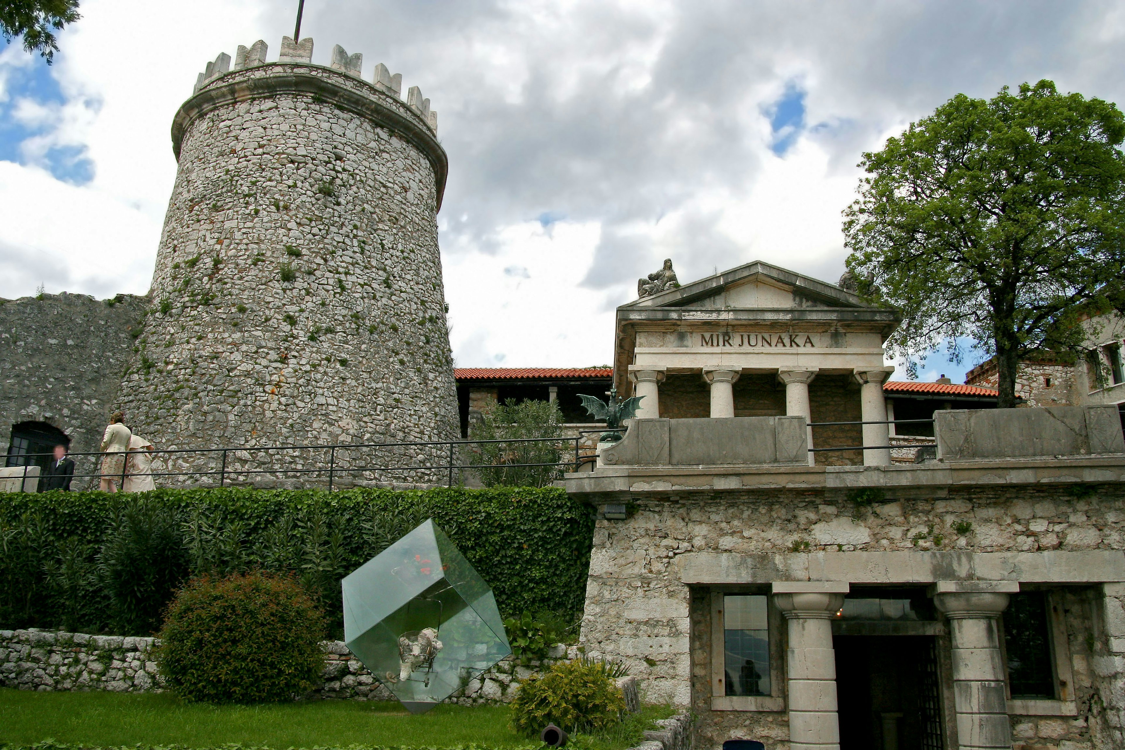 Historic stone tower and ancient building in a scenic landscape with lush greenery and blue sky