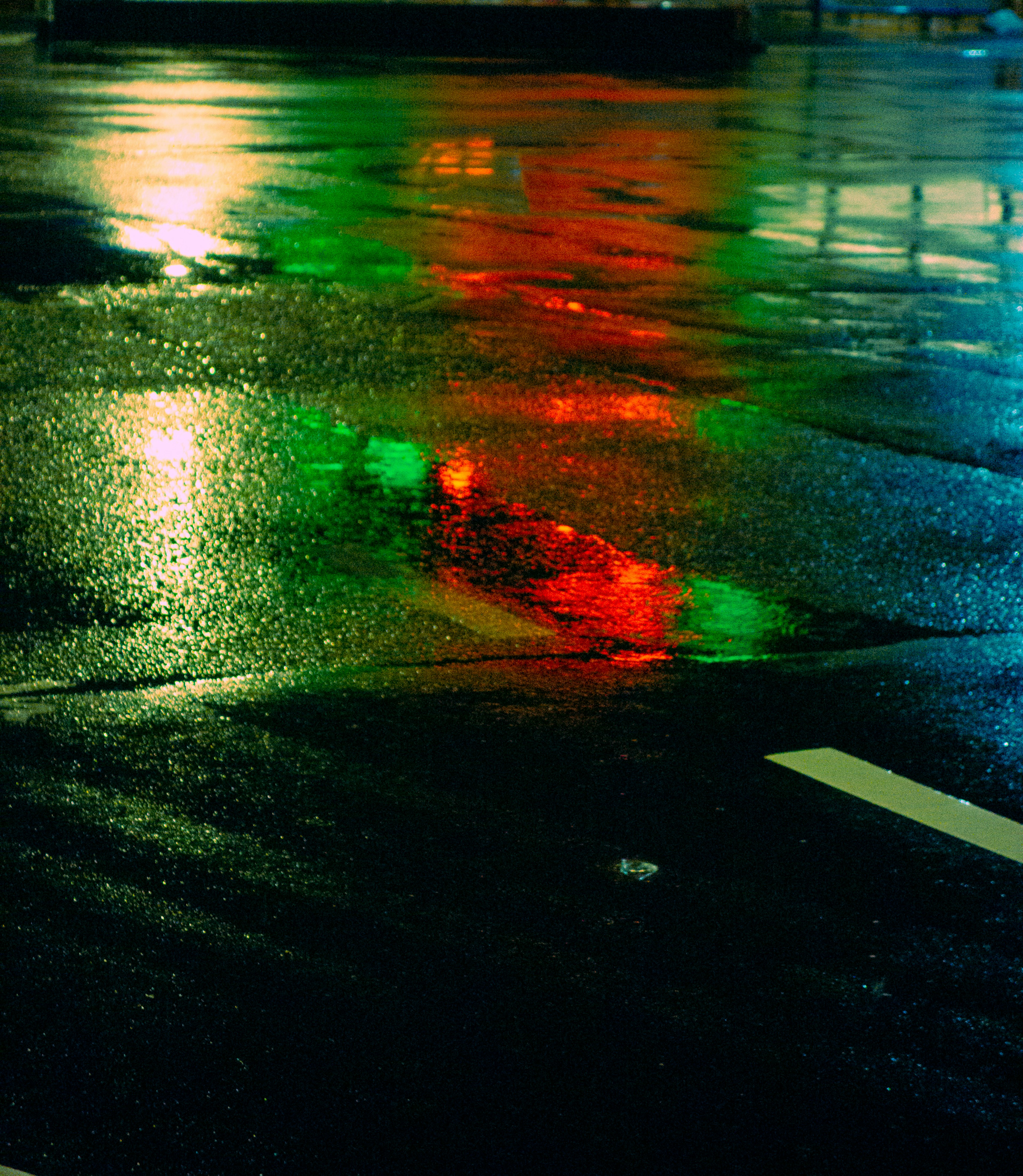 Reflet de lumières rouges et vertes sur une route mouillée