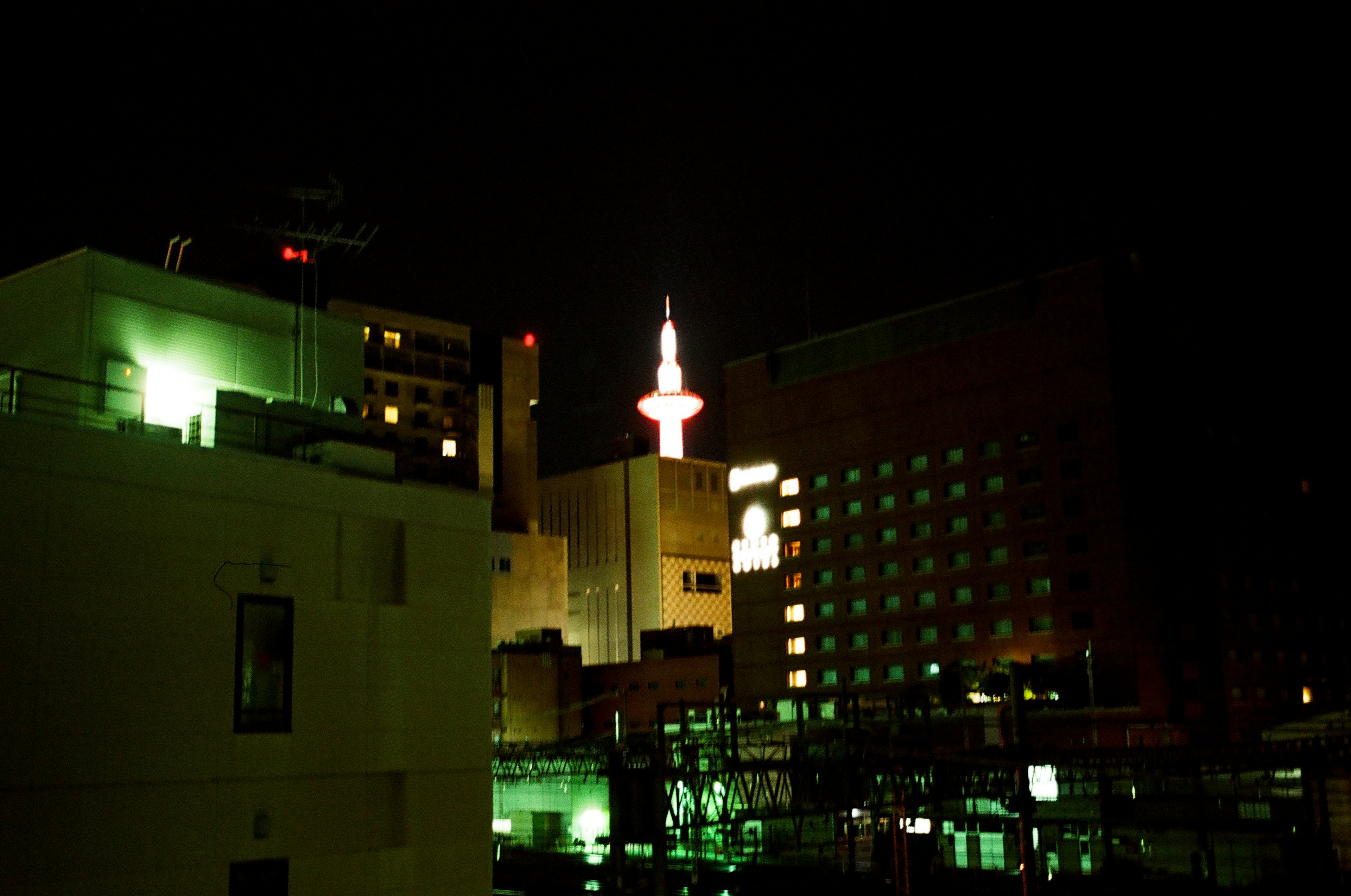 Night cityscape featuring a glowing tower and green lighting