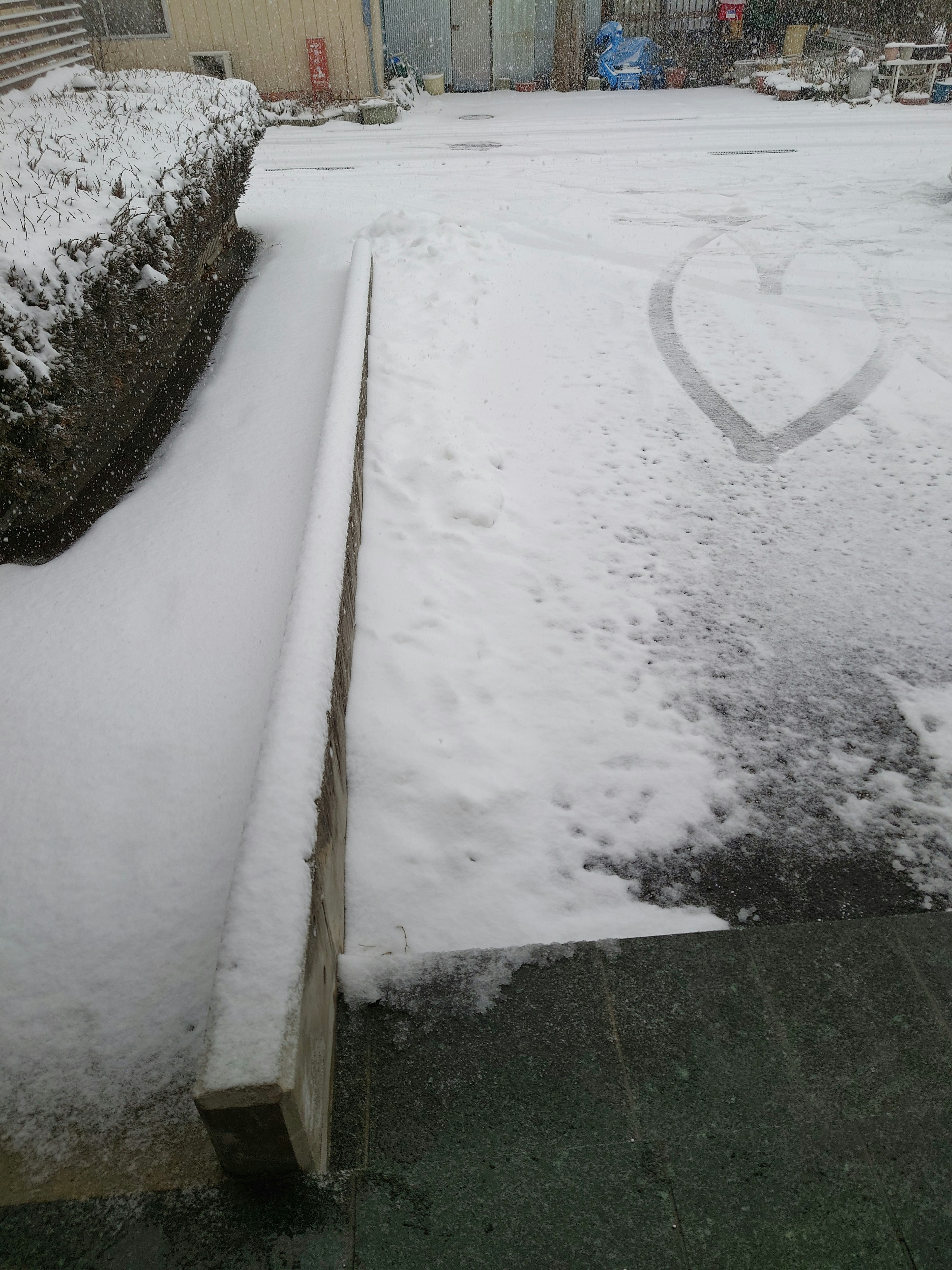 Snow-covered pathway with a stone wall on the side