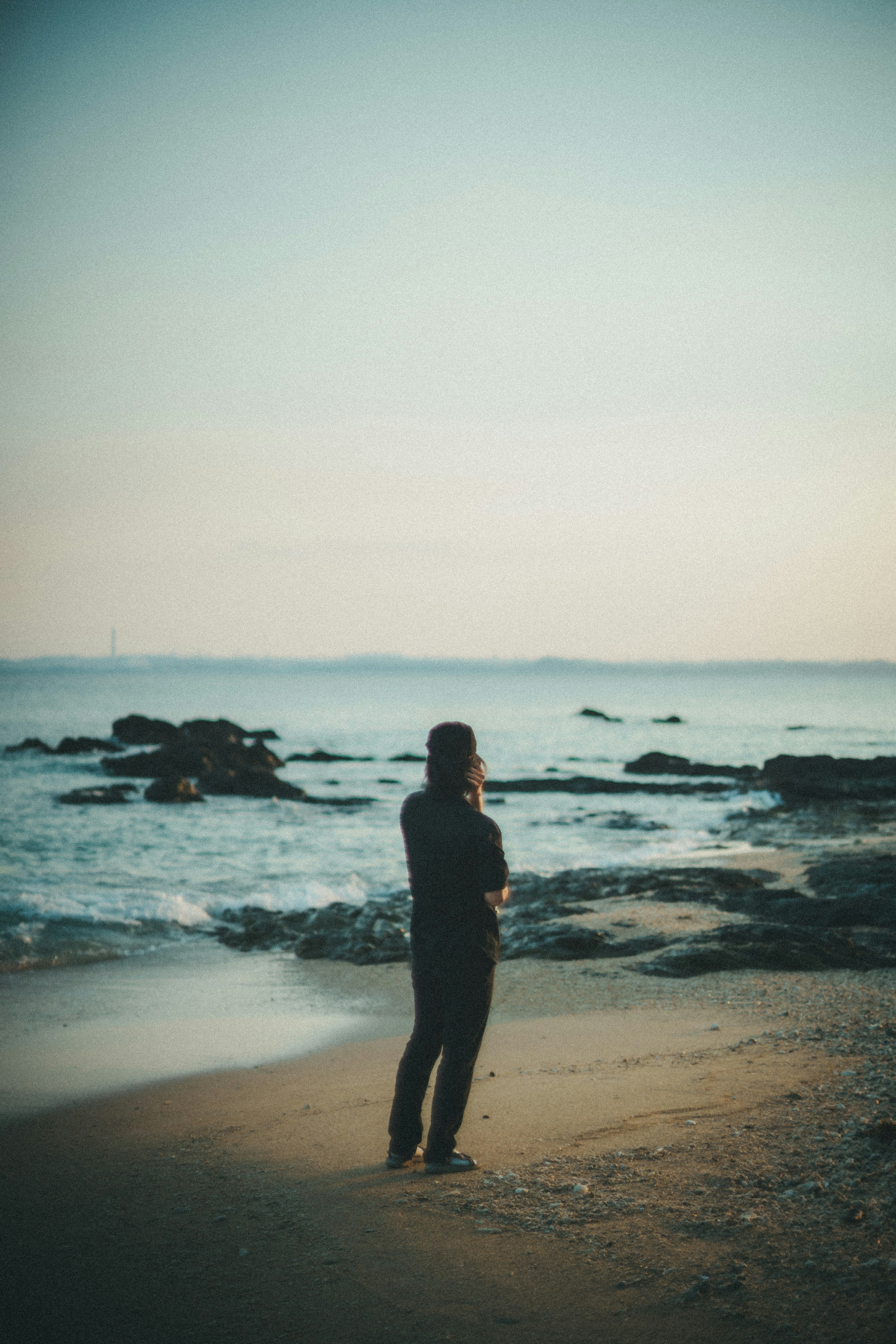 Silhouette d'une personne se tenant sur la plage avec un ciel calme