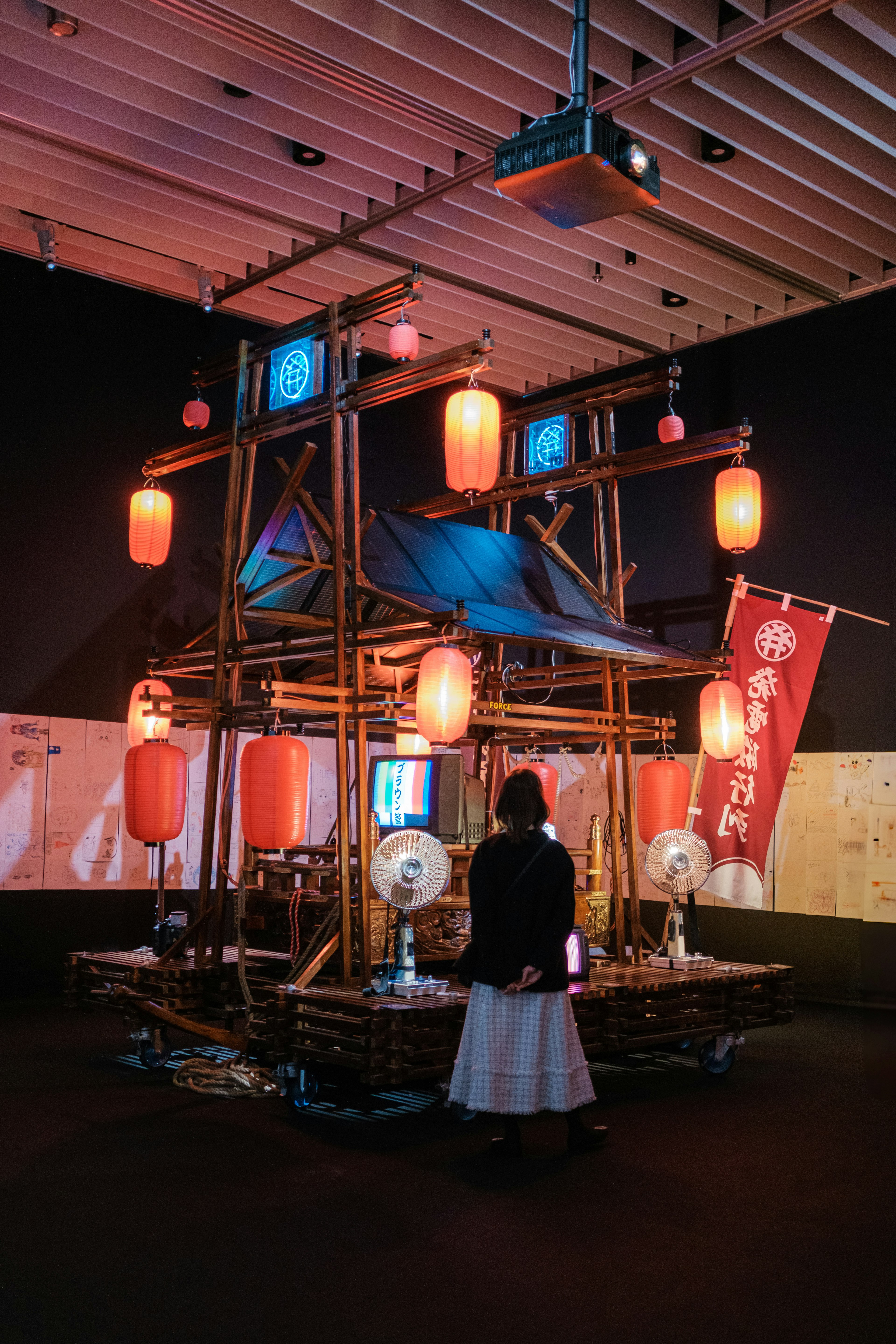 Une structure en bambou ornée de lanternes rouges et de tissu bleu dans un espace d'exposition