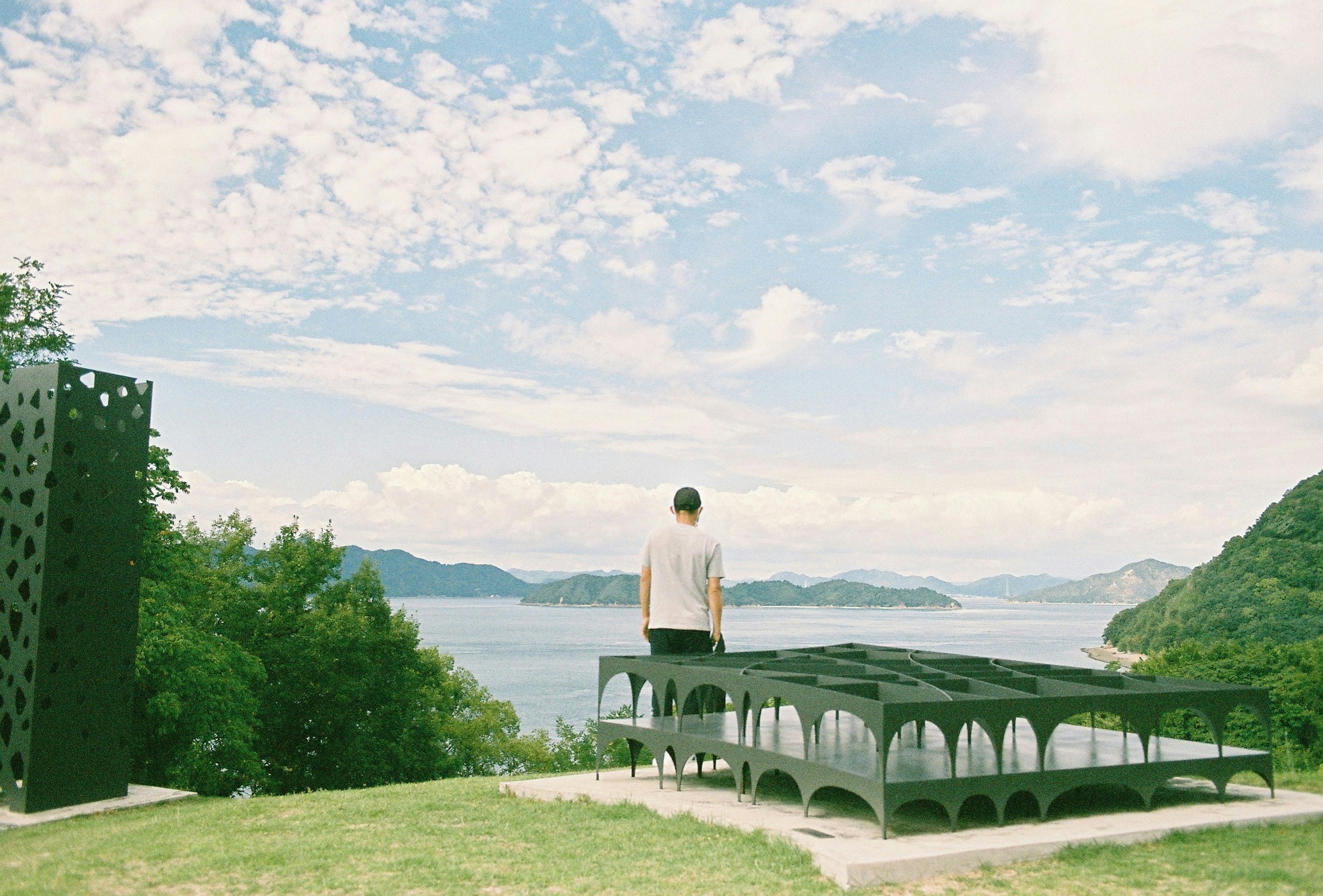 Person gazing at the sea with modern structure in green landscape