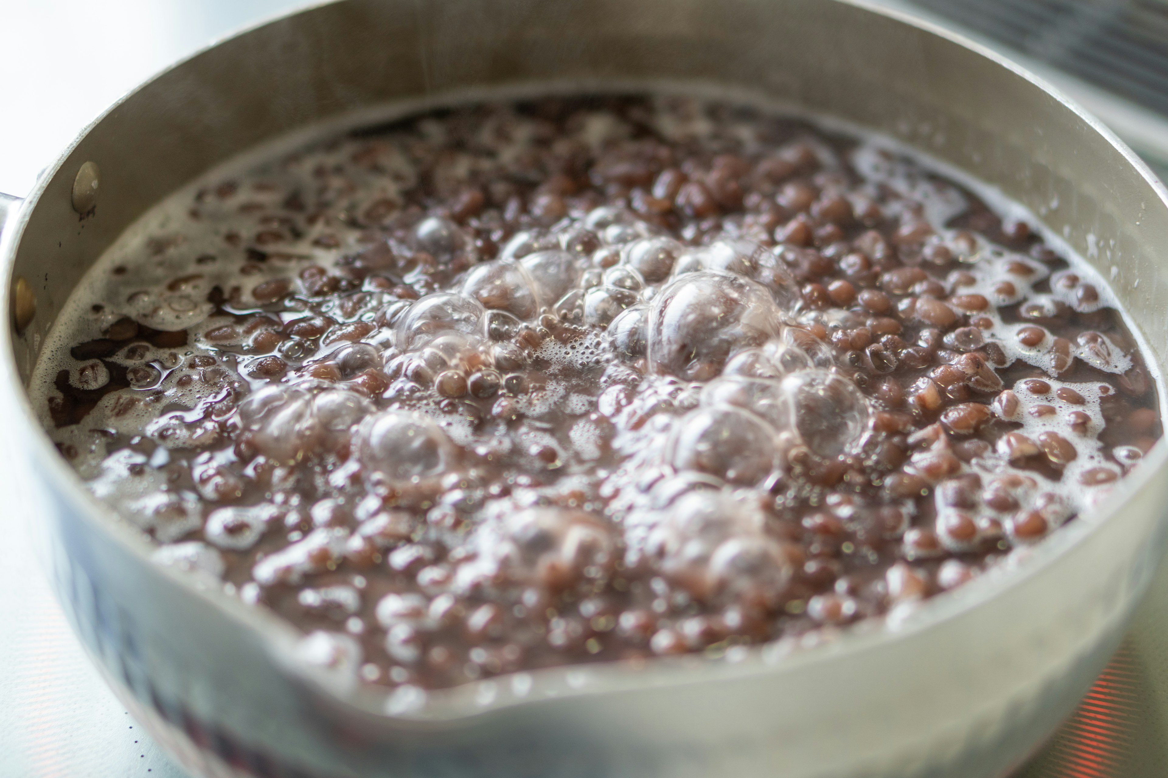 Image de haricots azuki bouillants dans une casserole avec des bulles