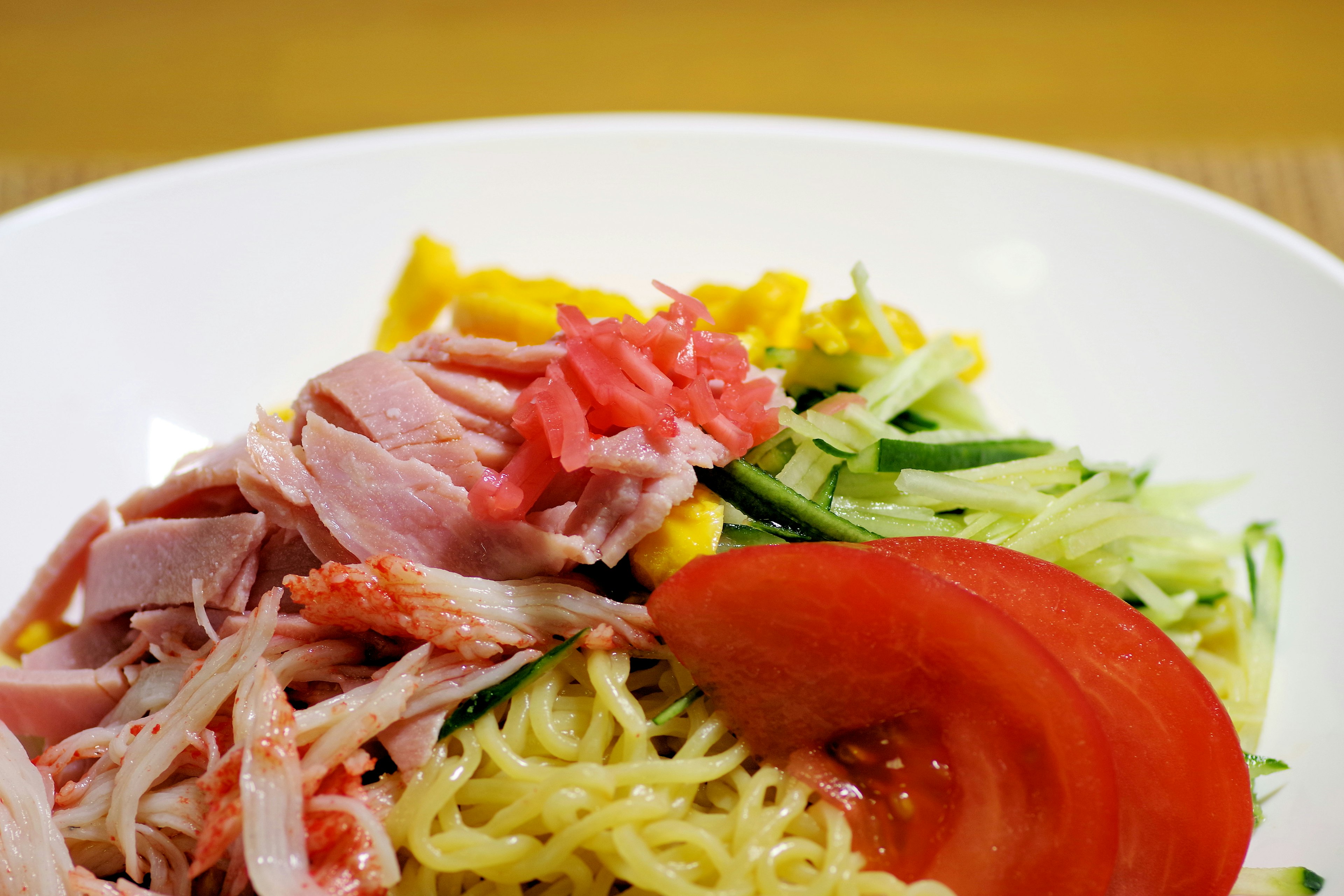 차가운 중국 국수 위에 닭고기, 토마토, 오이, 계란, 절인 생강이 올려진 요리