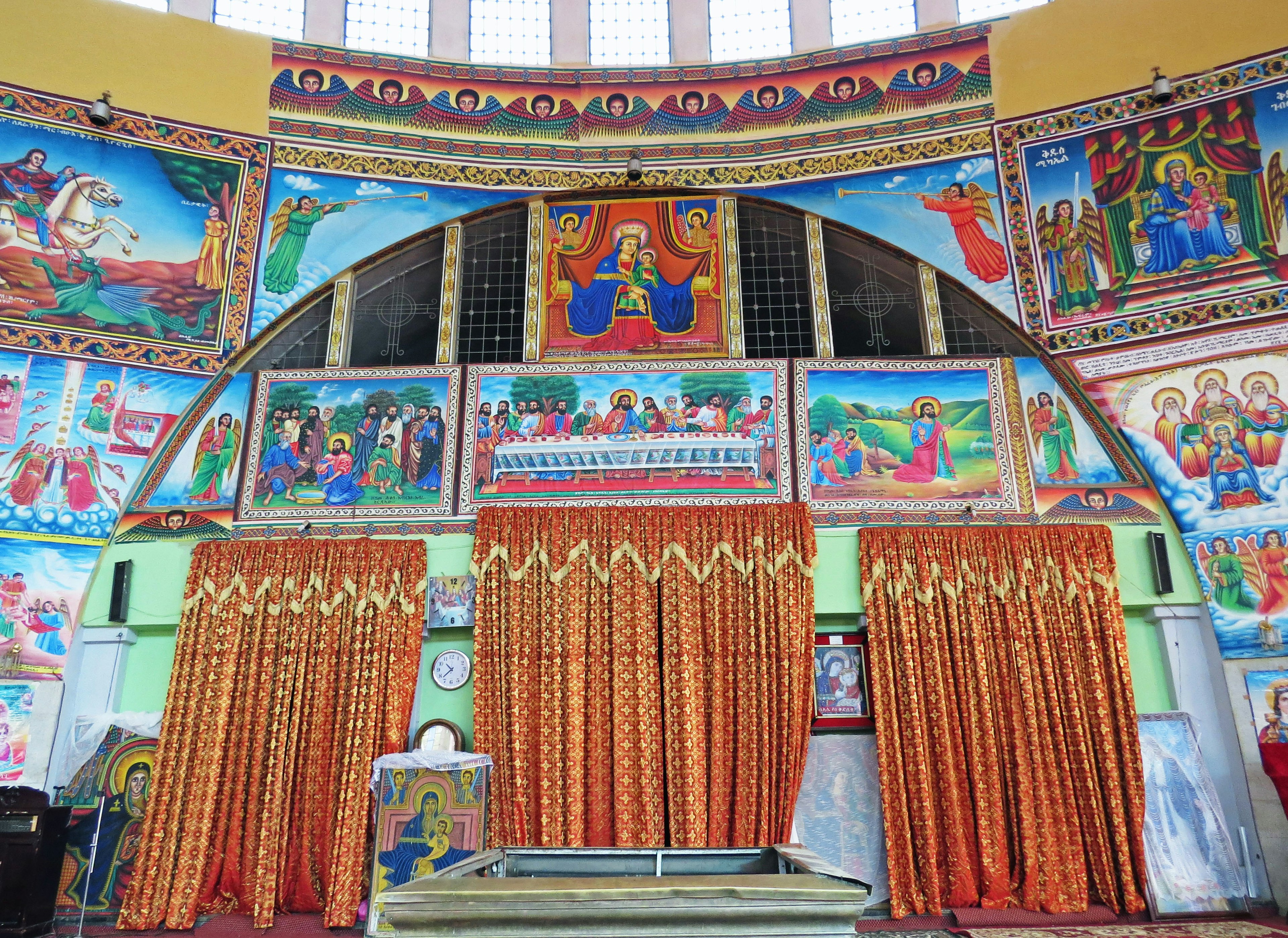 Interior of a church with colorful murals and golden curtains