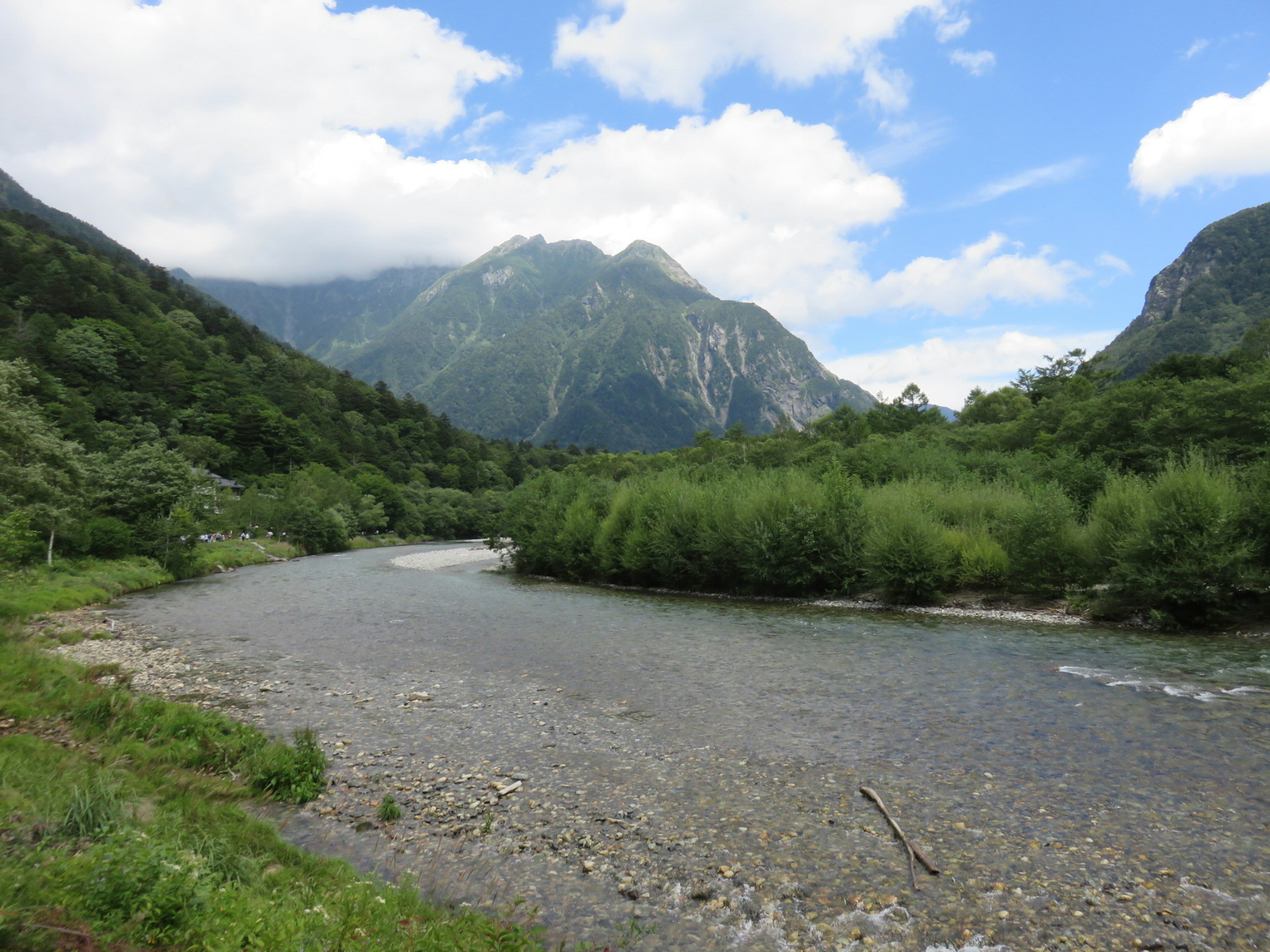 青い空と白い雲の下で流れる川と山々の風景