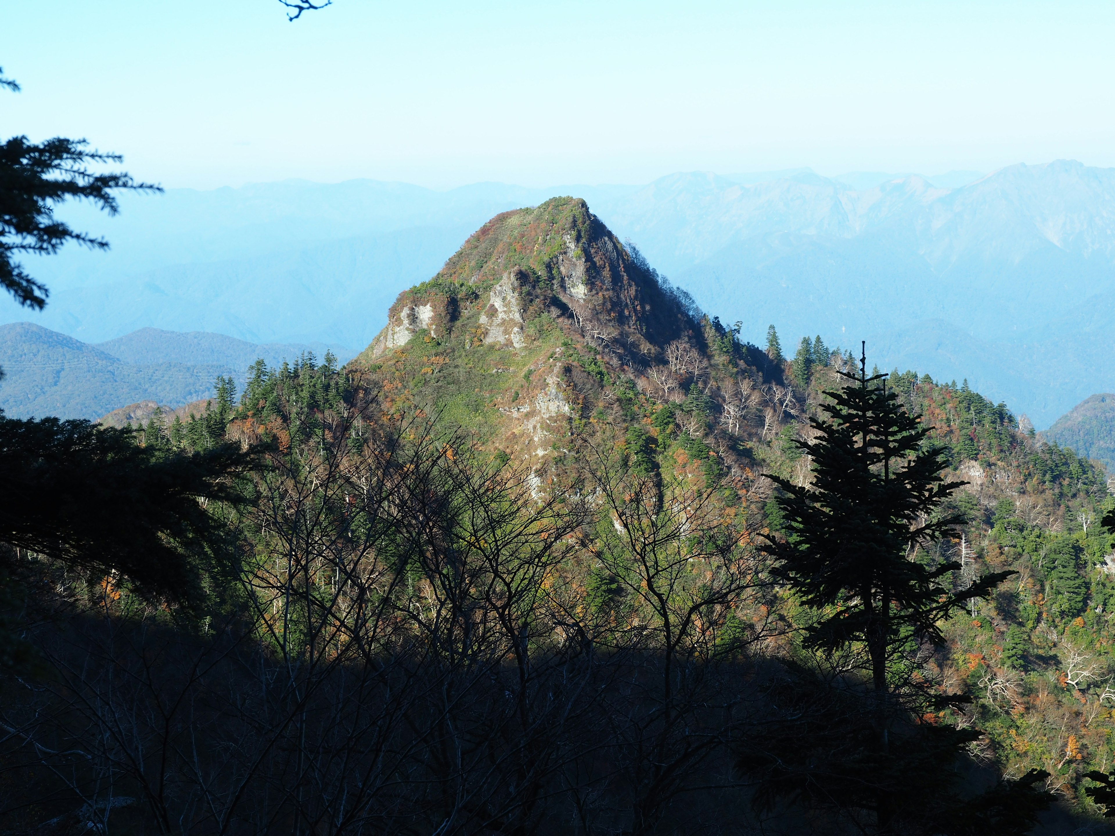 風景如畫的山峰，周圍環繞著綠色植物和藍天