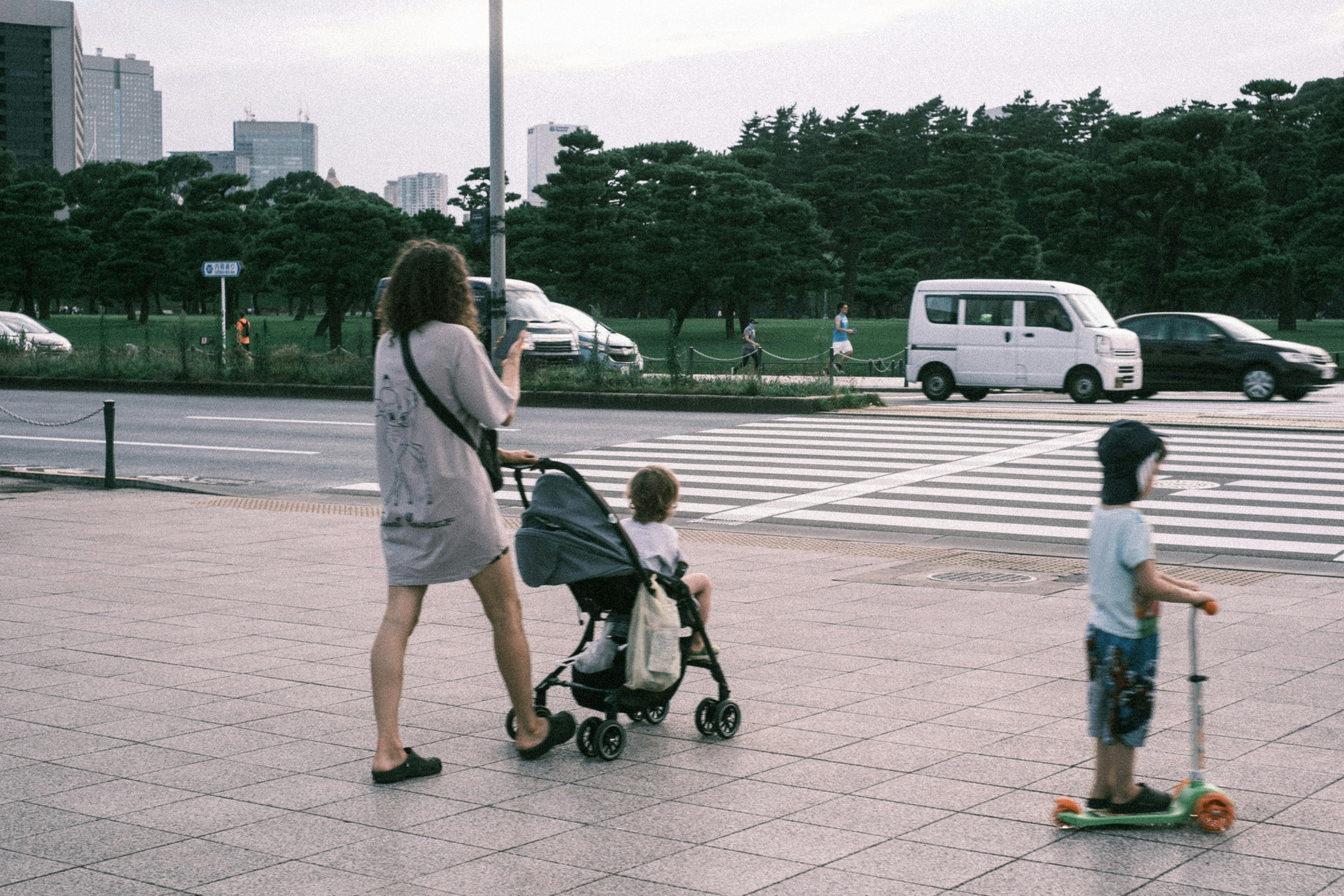 母親がベビーカーを押しながら子供と一緒にいる風景