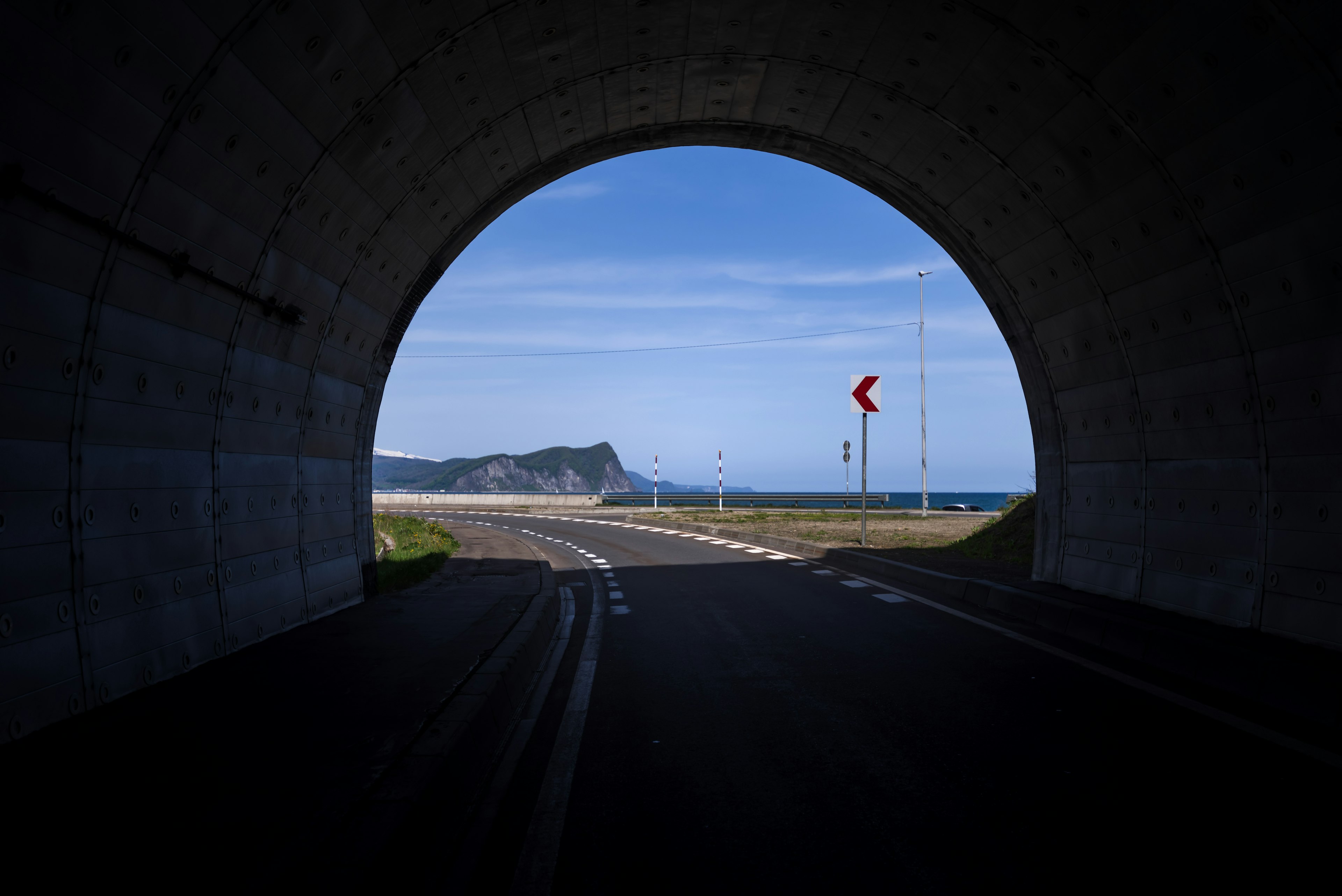 Vista a través de un arco de túnel que revela un paisaje marino y montañoso