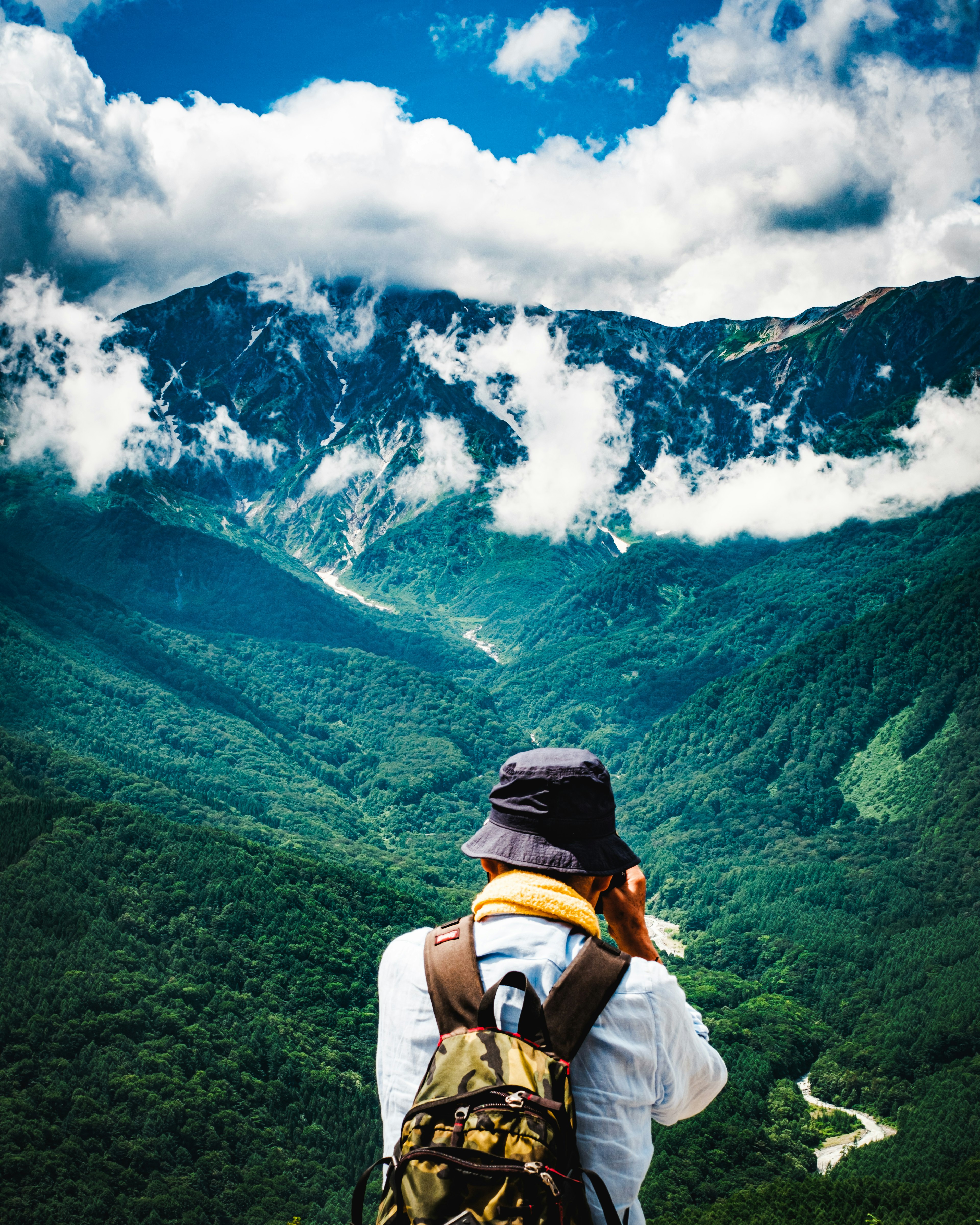 Hiker overlooking lush green mountains and cloudy sky