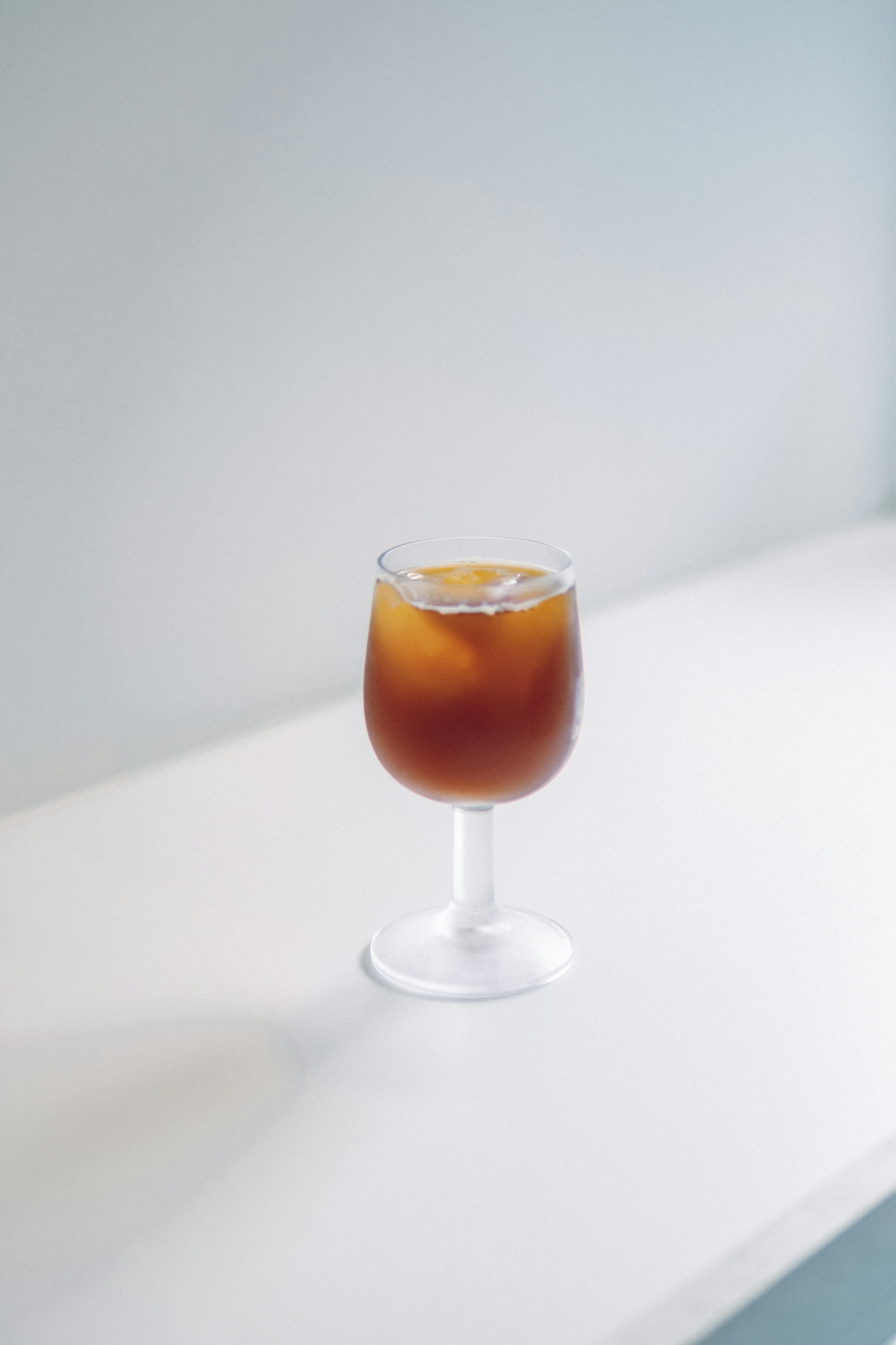 Té helado con hielo en un vaso sobre una mesa blanca