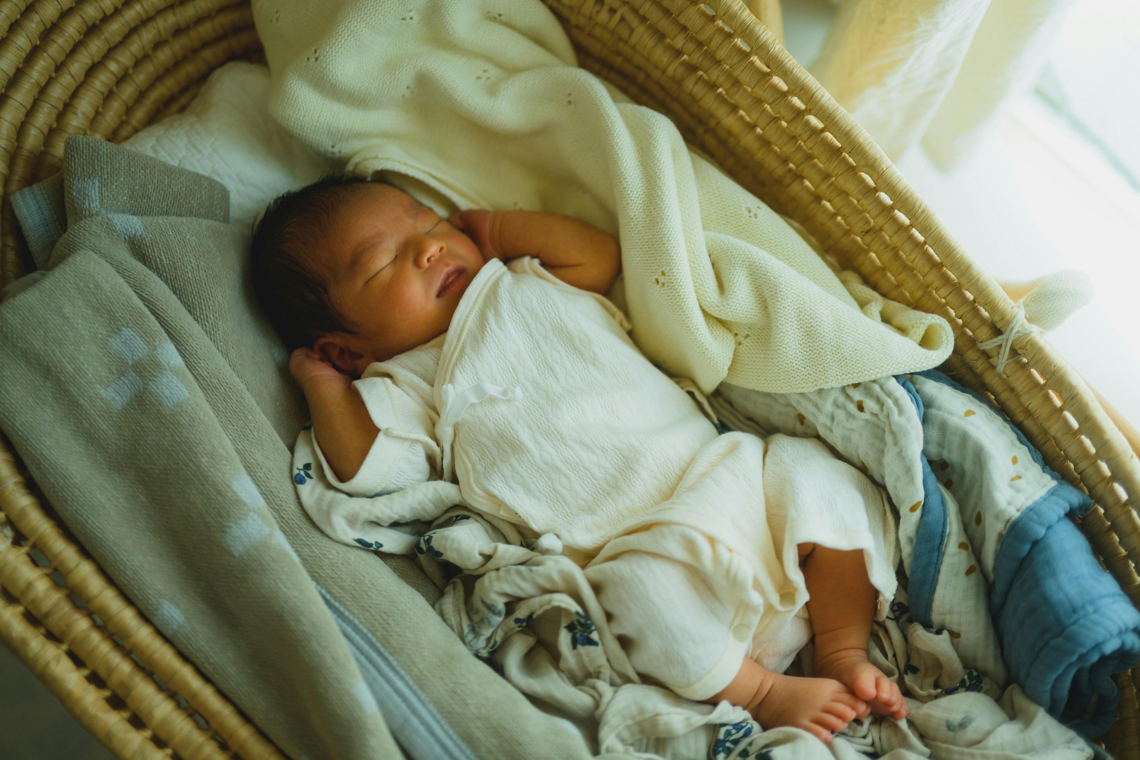 A baby sleeping in a basket wrapped in soft blankets