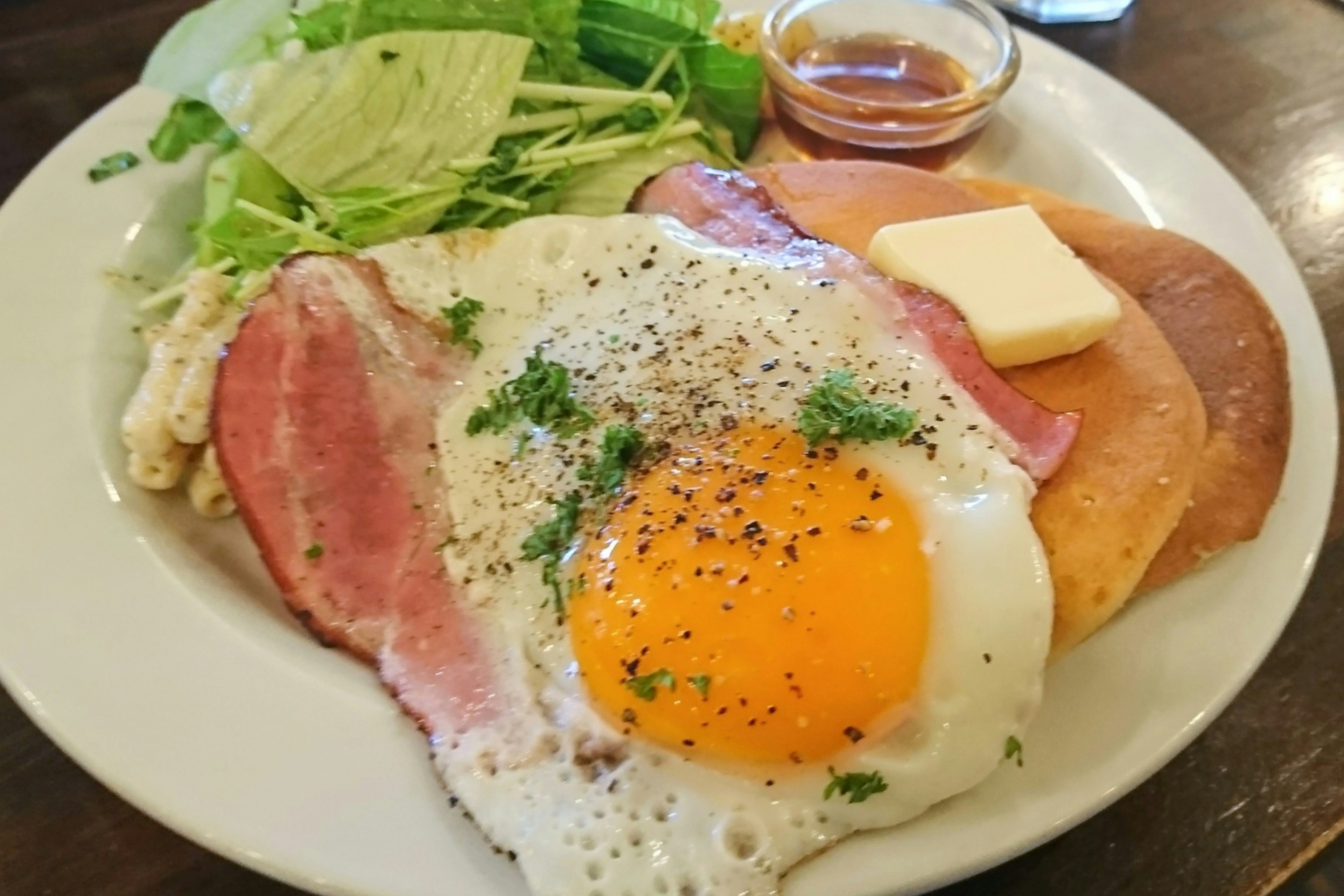 Plate featuring fried egg, ham, salad, and butter