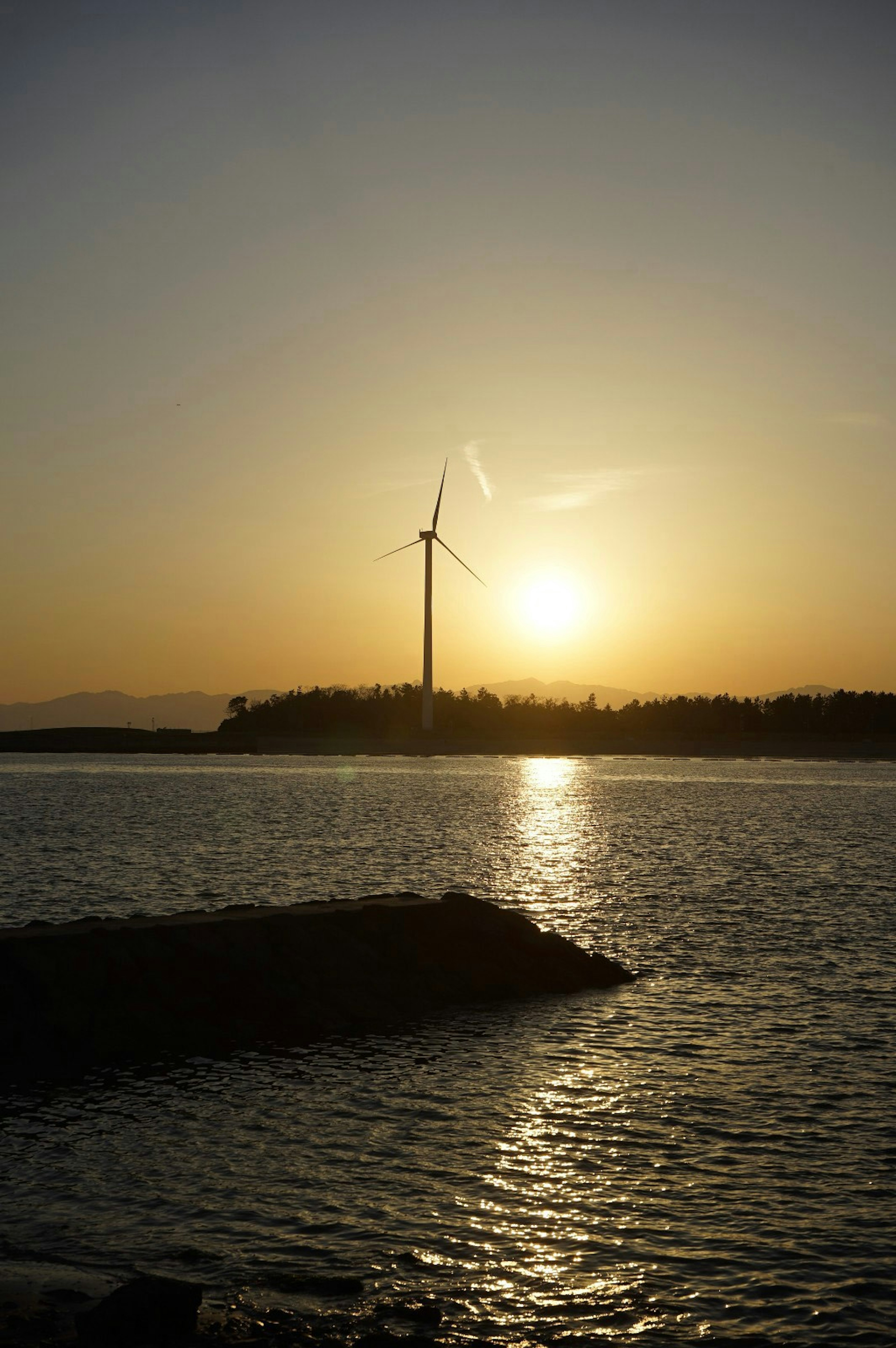 夕日を背景にした風力発電機と水面の美しい景色