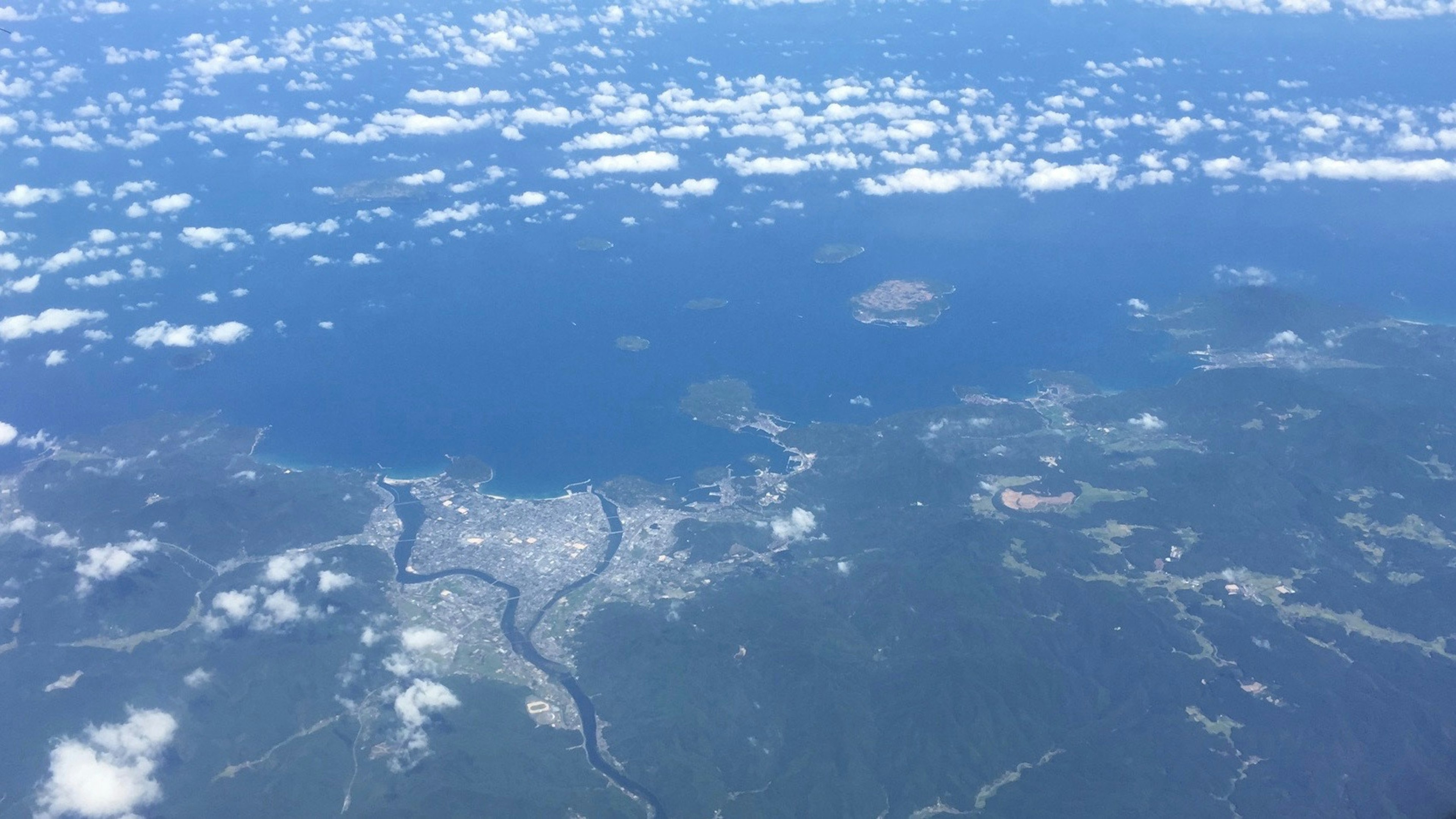 从空中看蓝色海洋和云朵，能看到岛屿和河流