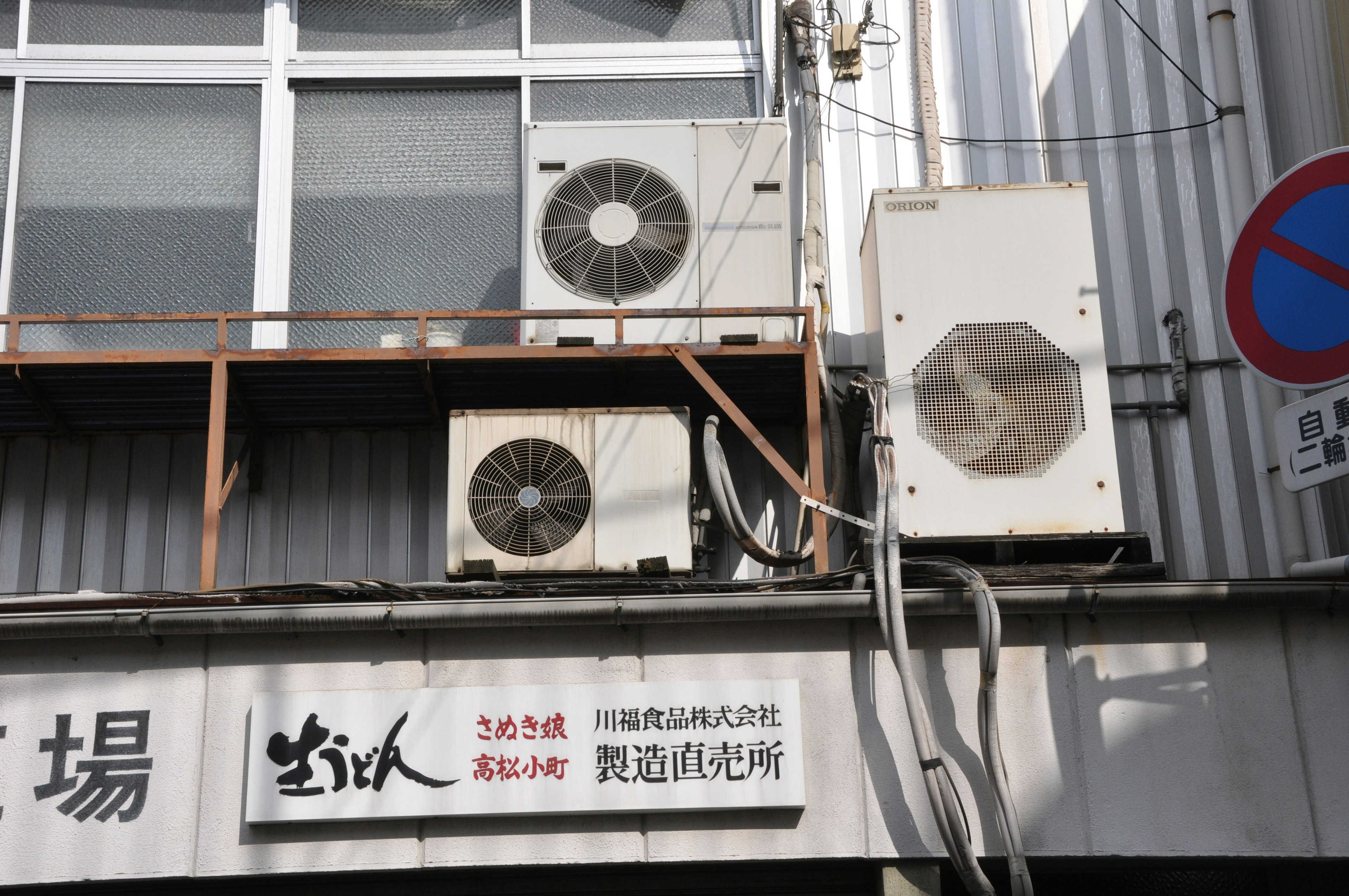 Image of air conditioning units mounted on a building exterior with a sign