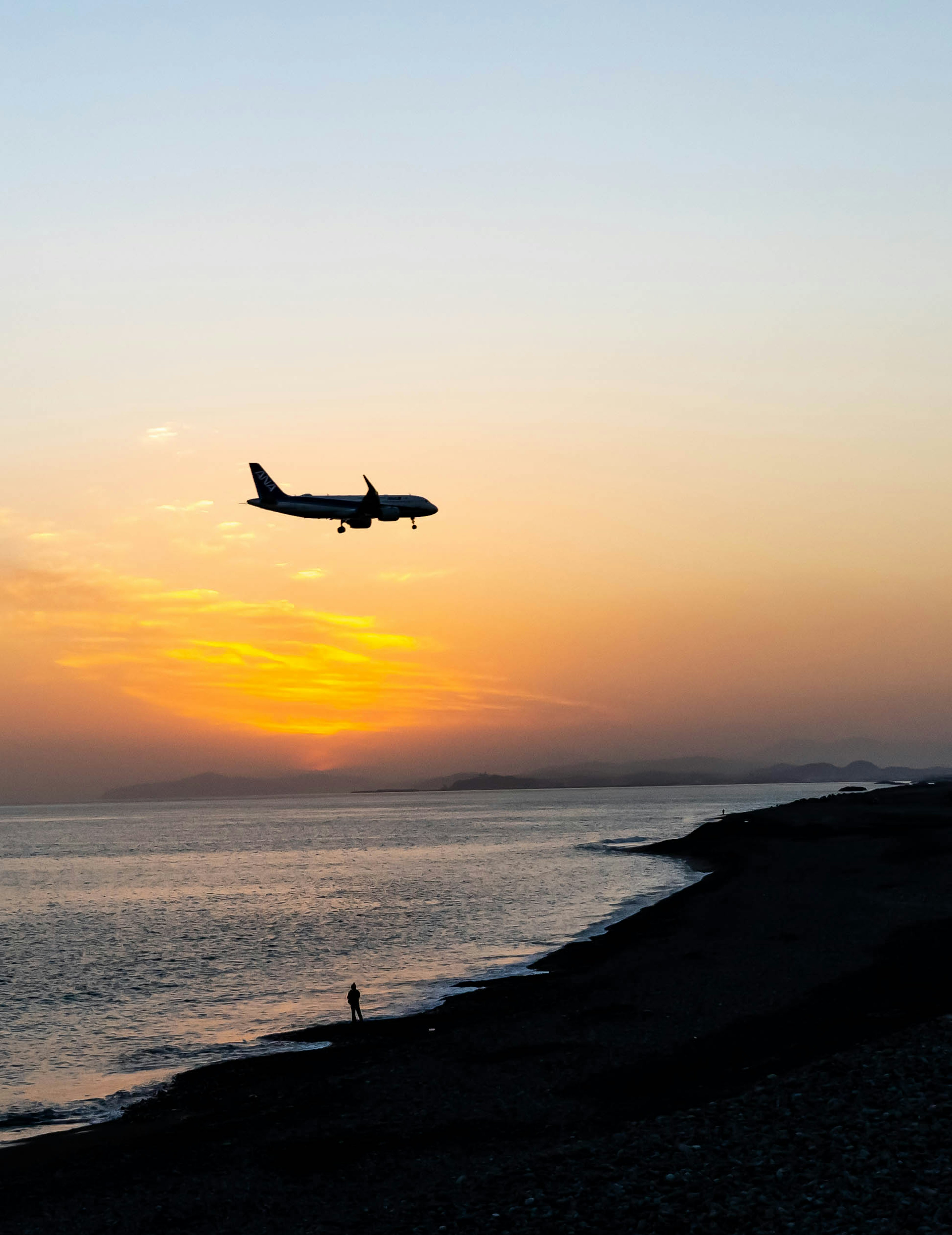 夕日を背景に飛行機が海上を飛ぶ美しい風景